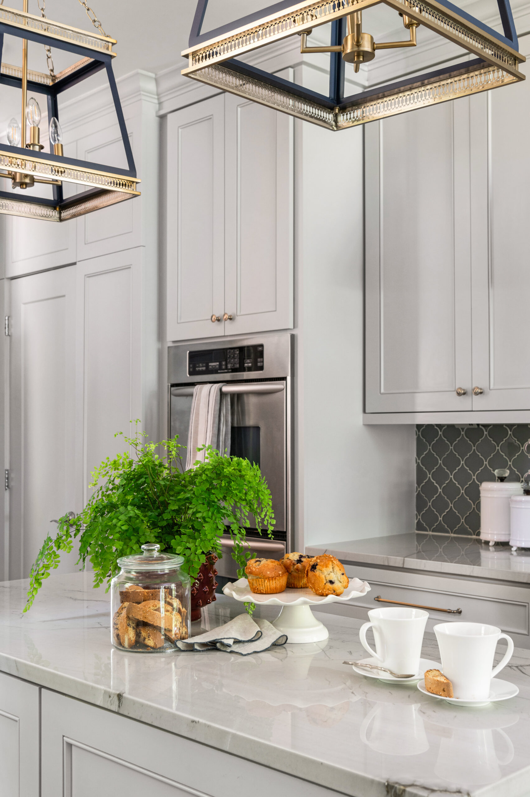 Sleek white kitchen interior design with white marble counters and coffee mugs and muffins laid out