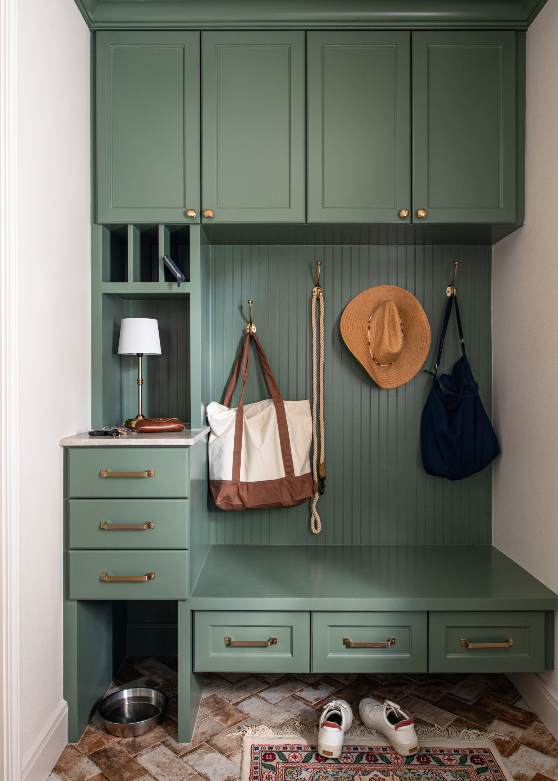 Green painted modern mudroom interior design with hanging clothes and bags