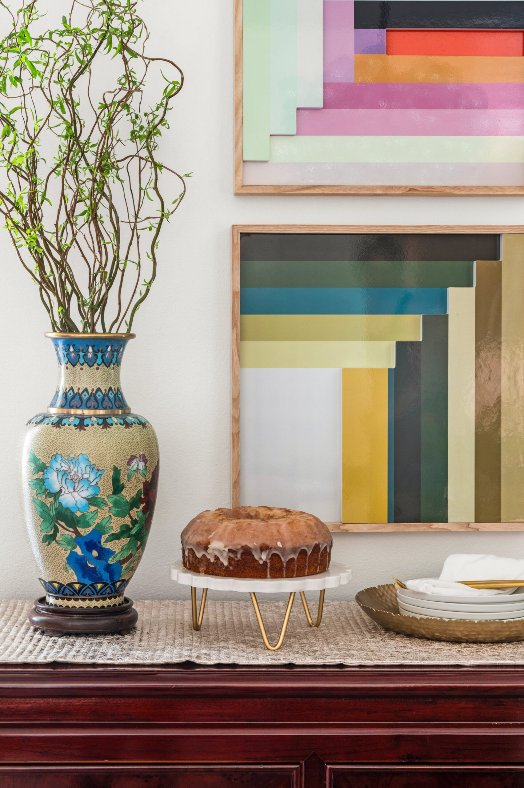 Colorful interior design of a dining room space with colorful artwork and bundt cake sitting on side table