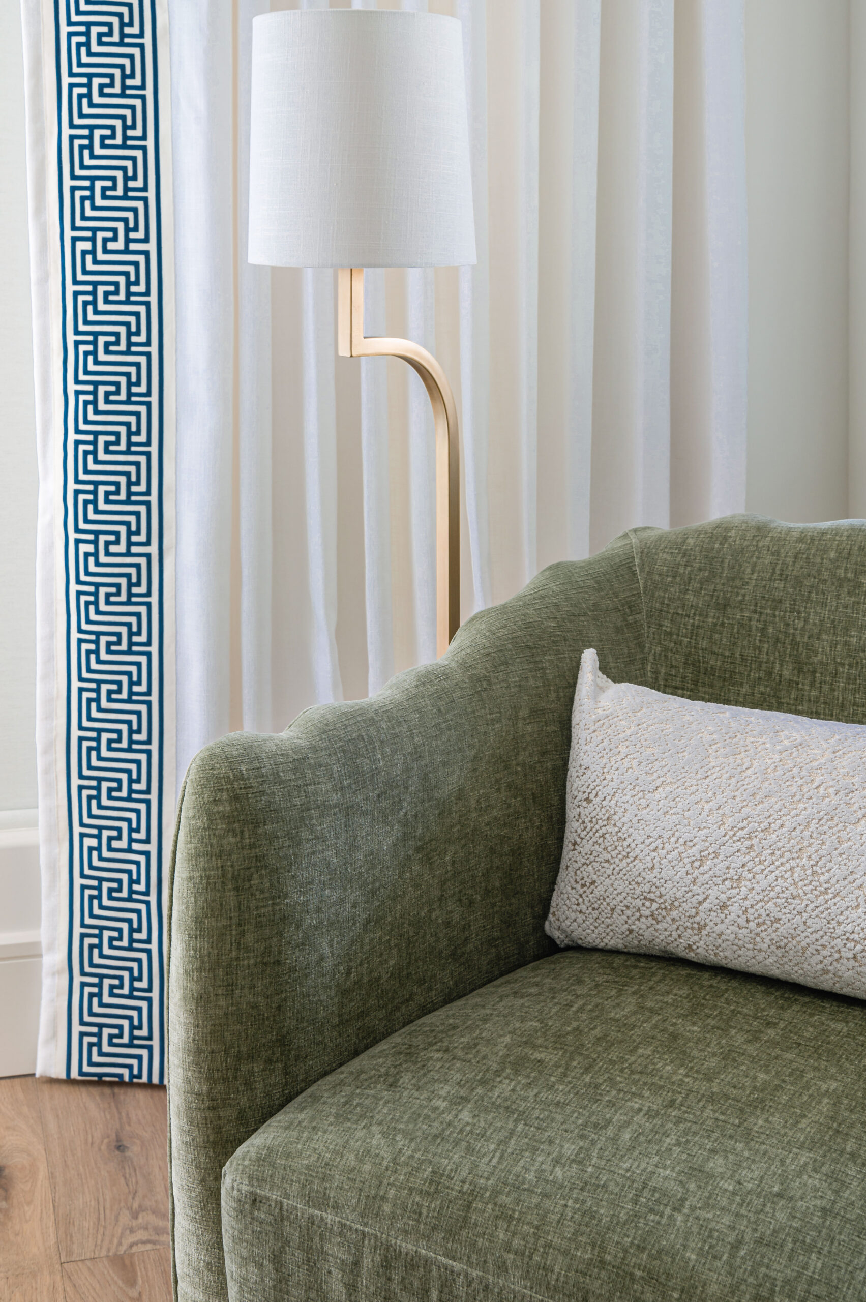 A detailed close-up of a soft green sofa paired with modern lighting, showcasing the refined yet relaxed feel of Texas interior design.