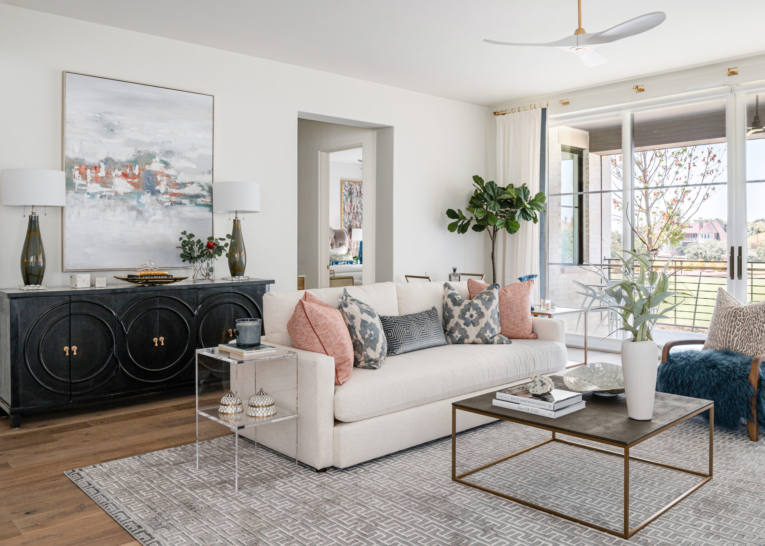 Open concept living room and kitchen: A modern, airy Texas interior design living room with cozy, plush seating, a chic coffee table, and a view of the open-concept kitchen featuring white cabinetry and warm wood elements.