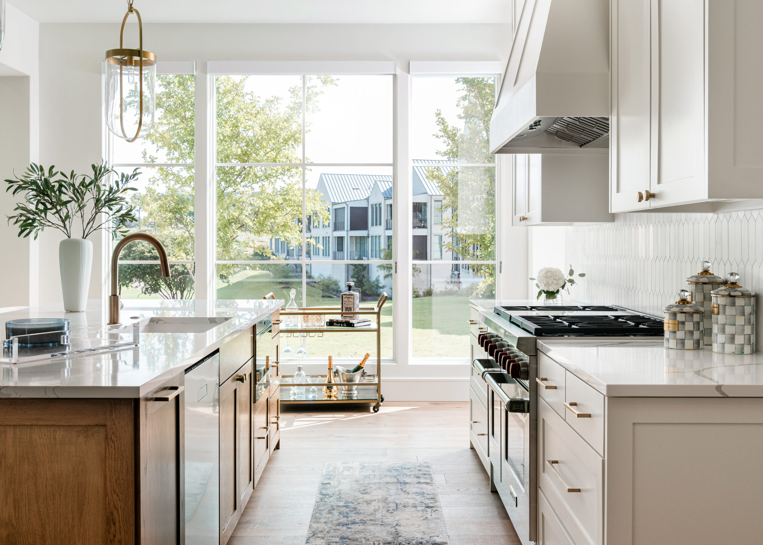 Bright and airy Texas interior design kitchen featuring large windows, modern appliances, white cabinetry, and a central island with natural wood accents, blending contemporary style with warm, inviting elements.