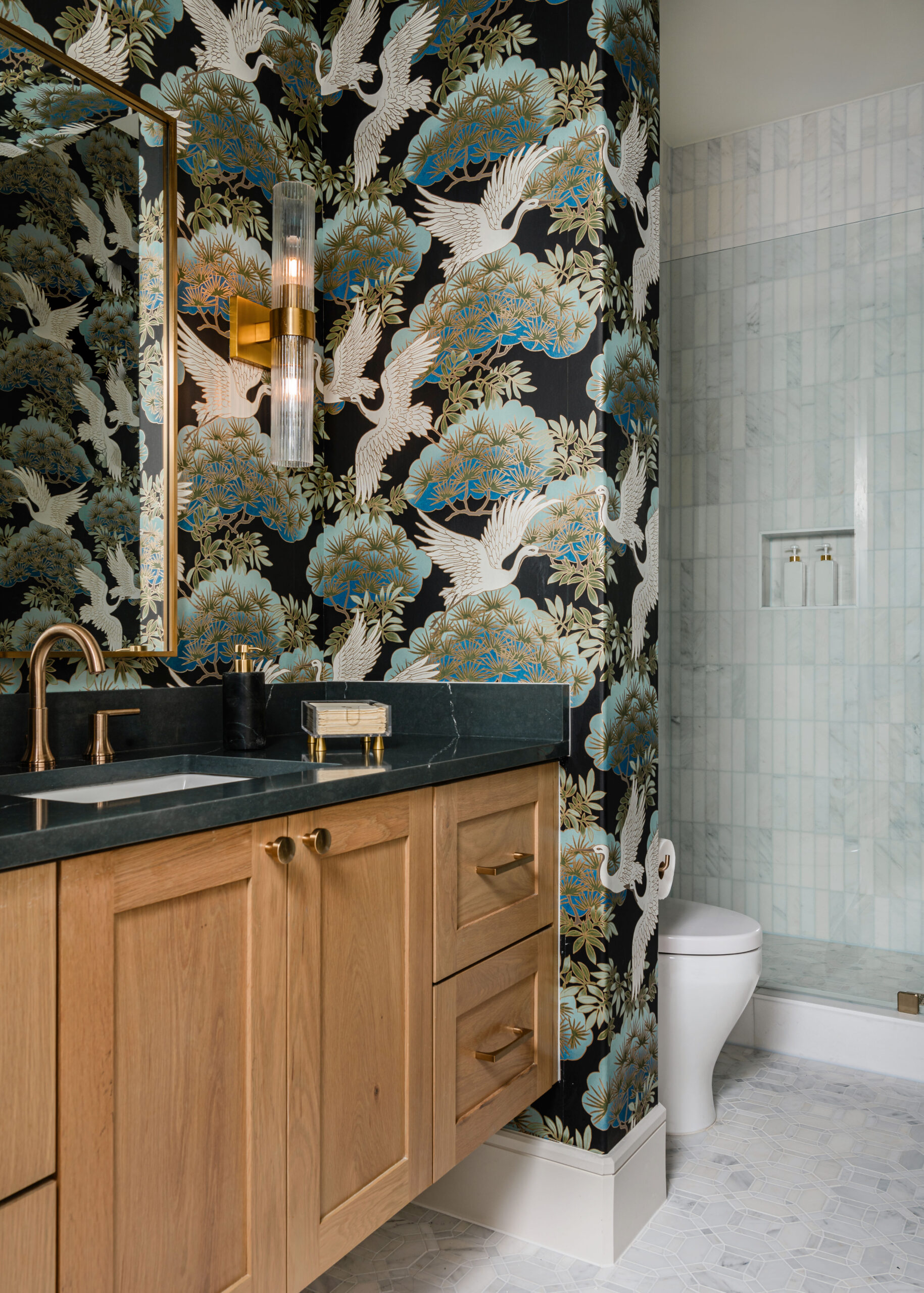 Bold wallpaper and wooden bathroom vanity: A chic Texas interior design bathroom featuring a bold, nature-inspired wallpaper paired with a wooden vanity and black countertops for a striking look.