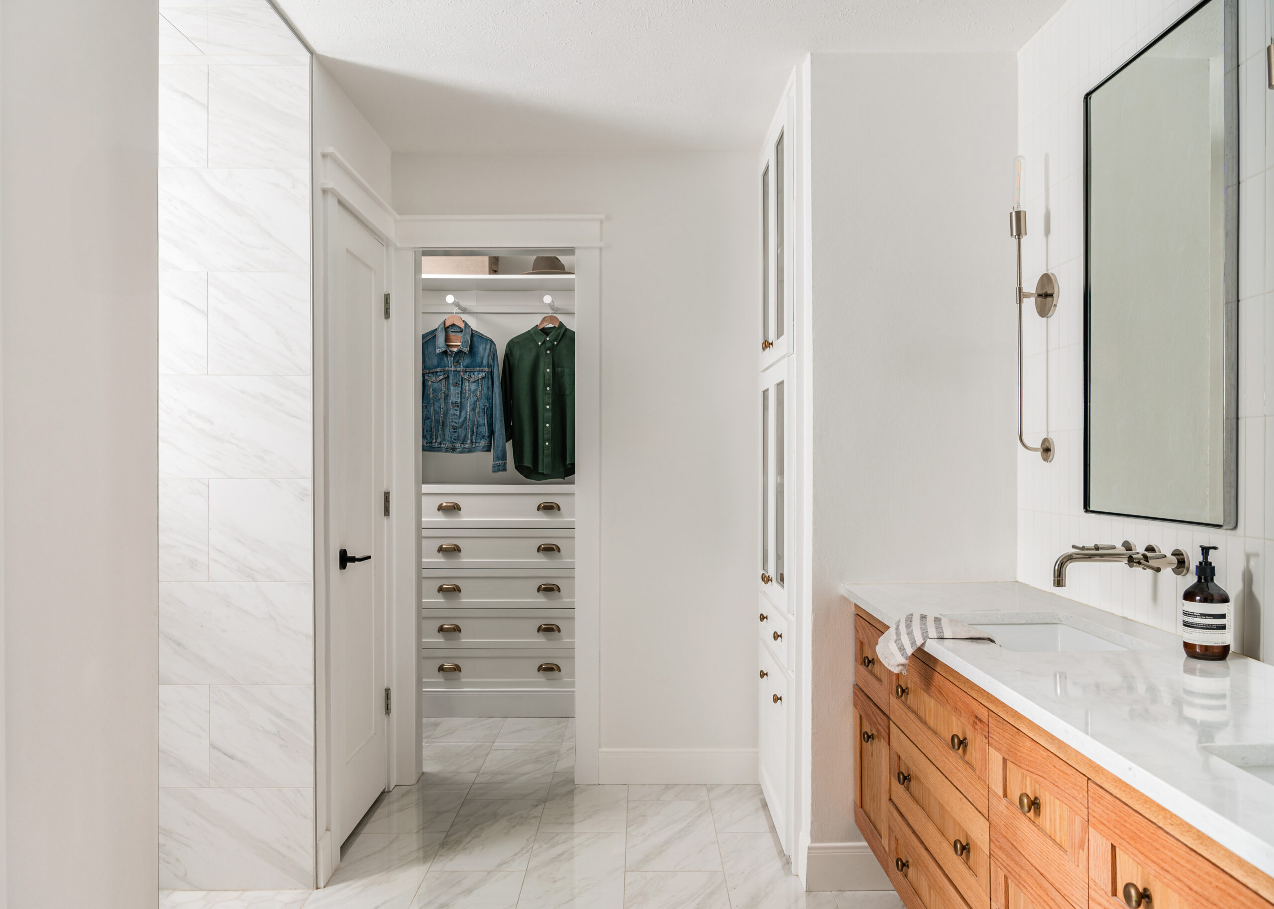 Bright white luxury bathroom interior design with wood cabinets and white counters