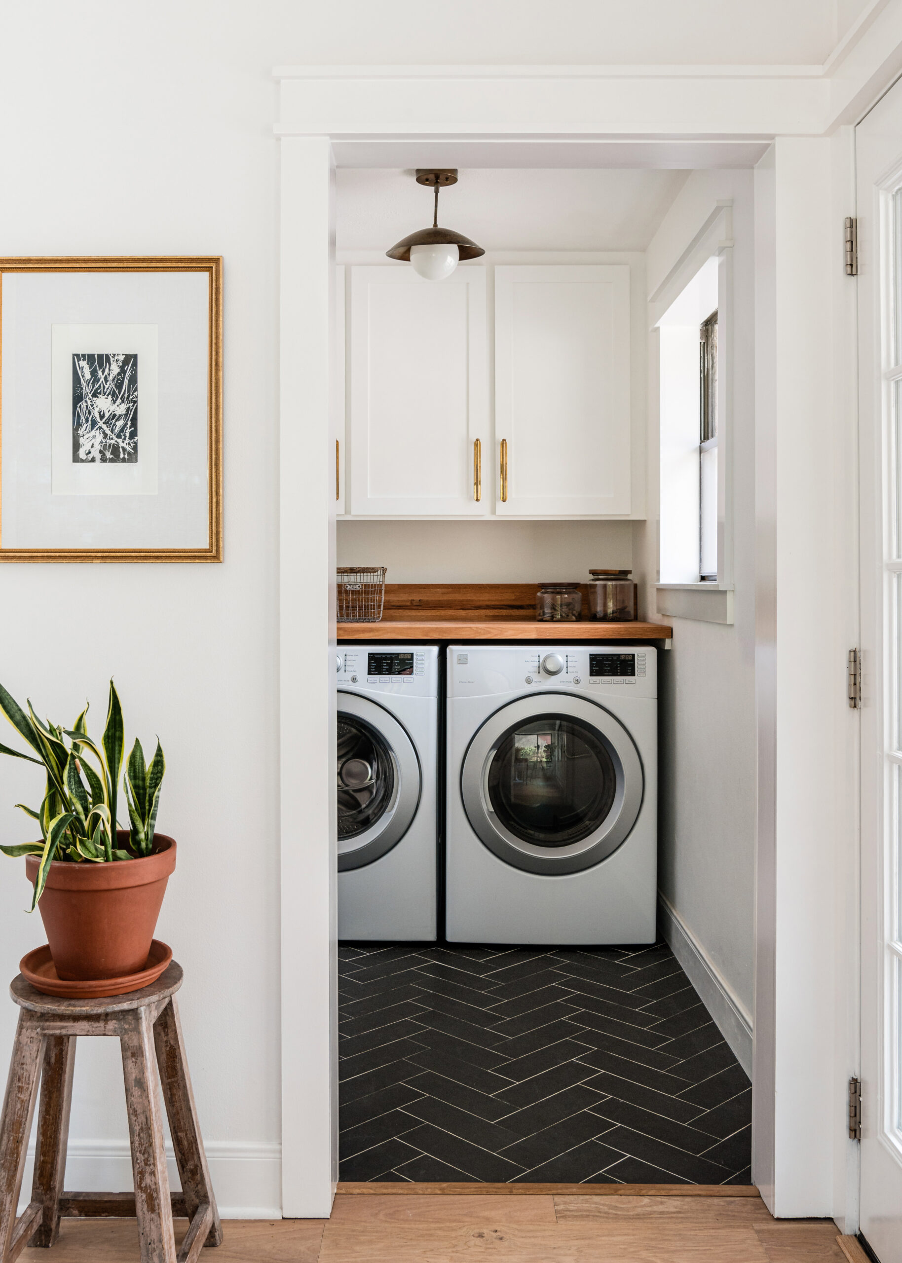 Modern laundry room interior design with black floor tile and gold accents