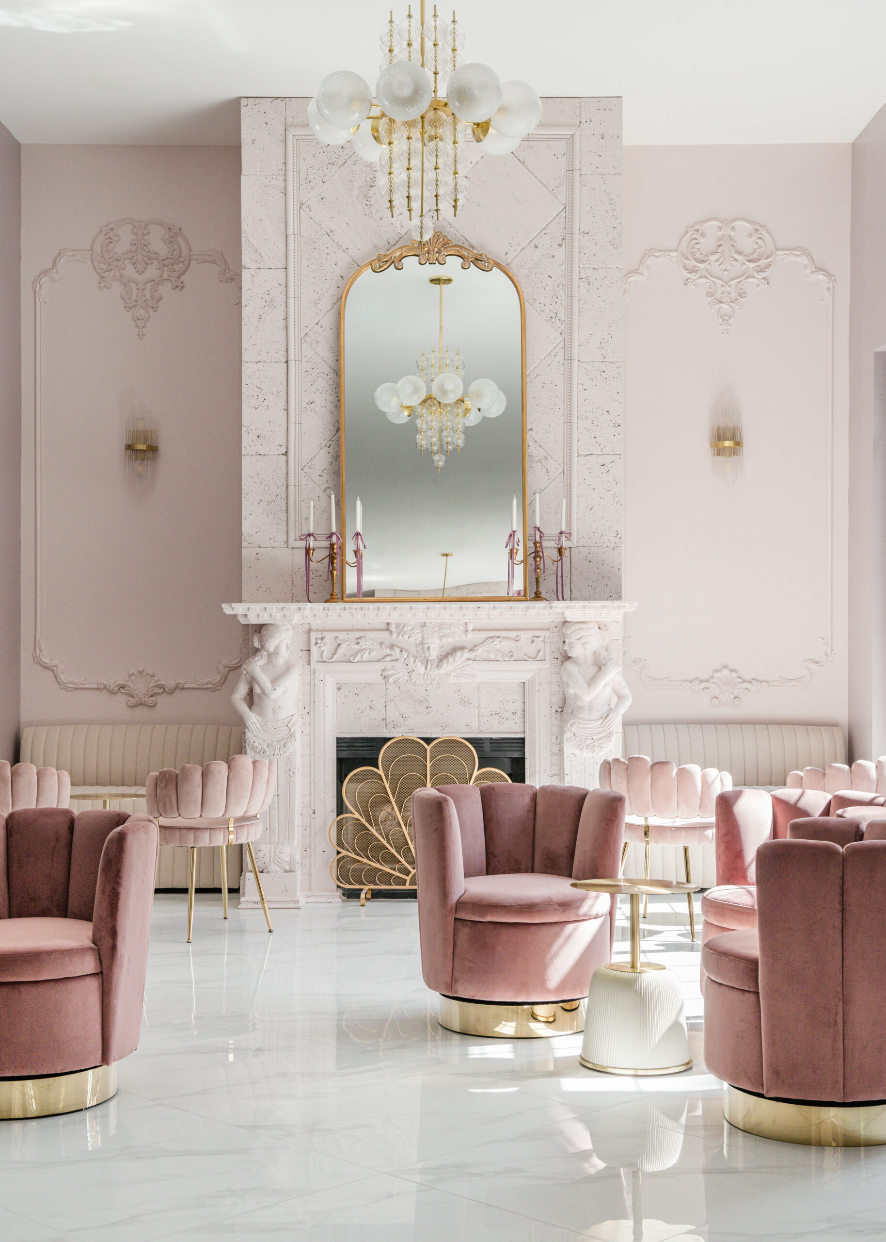 A luxurious bridal lounge area with a grand fireplace, flanked by statues and a gold peacock-style fireguard.