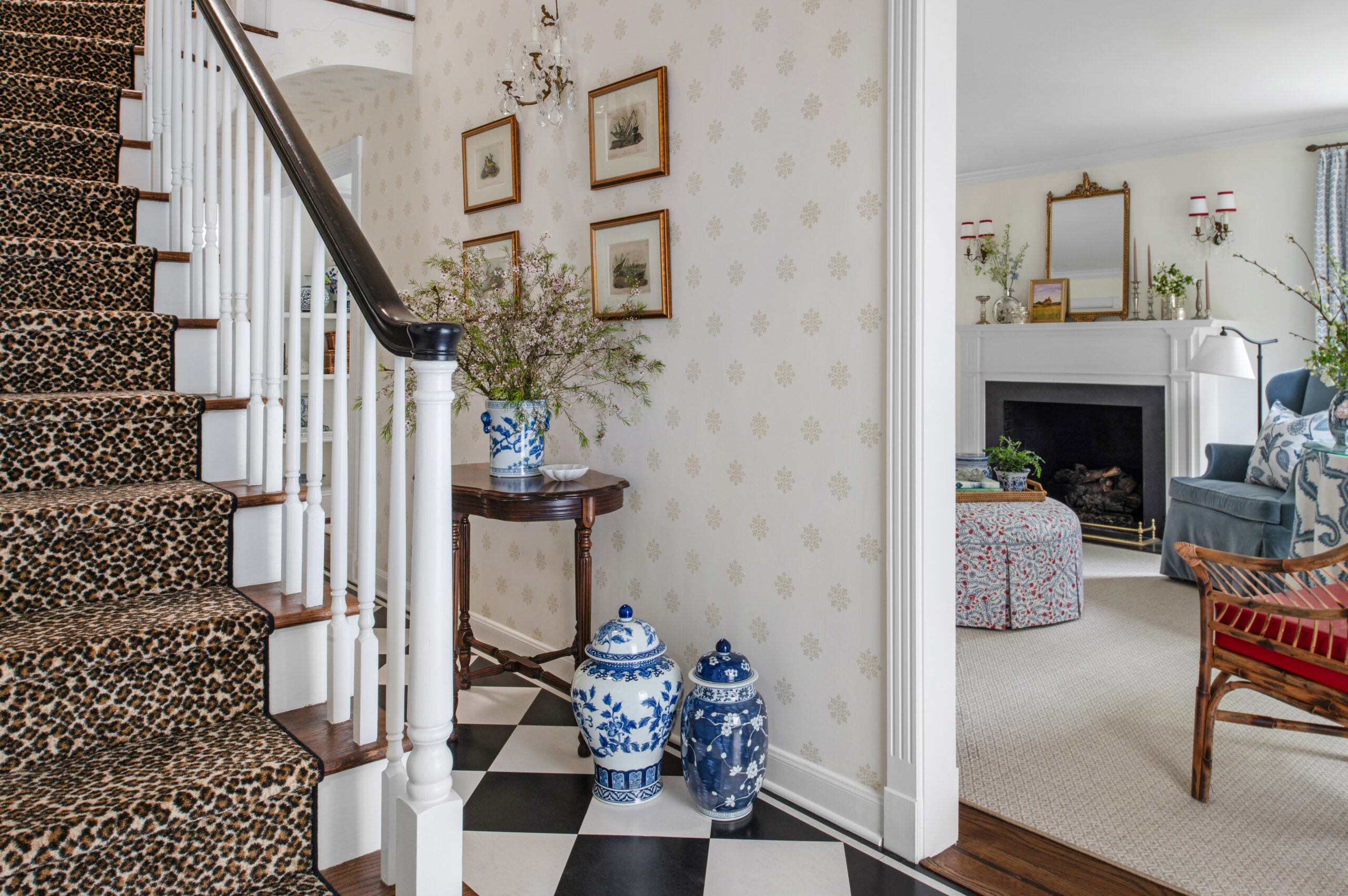 A charming hallway featuring a leopard-print carpeted staircase, complemented by a black-and-white checkered floor. Traditional blue and white porcelain vases at the base of the stairs add an eclectic and sophisticated element to the space, making it a prime example of classic yet bold design.