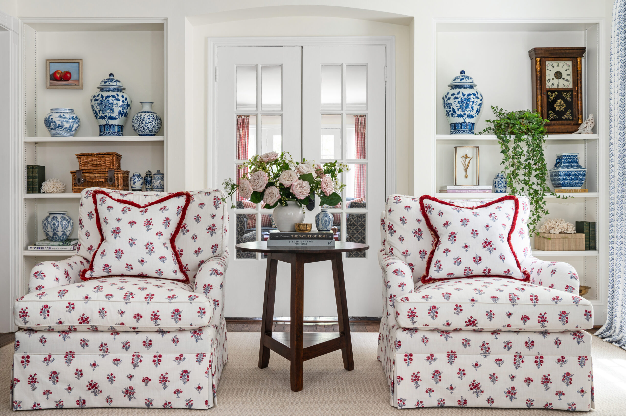 A close-up of a vibrant living room space, with a floral ottoman, soft curtains, and fresh flowers on a nearby table. The design mixes patterns and textures seamlessly, creating a layered and lived-in feel perfect for Interior Design Photography Licensing. The soft lighting accentuates the room's warmth and character.

