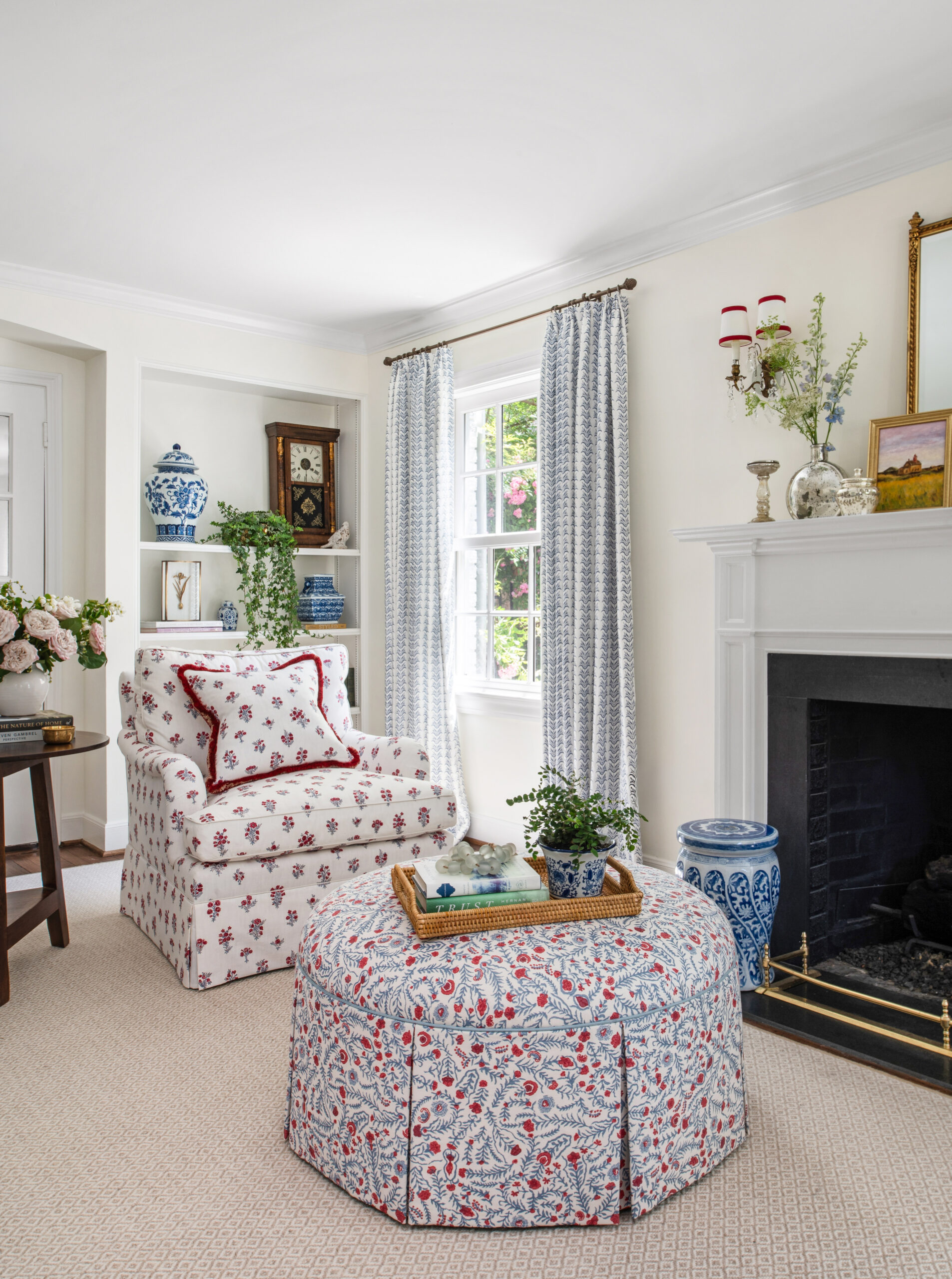 A close-up of a vibrant living room space, with a floral ottoman, soft curtains, and fresh flowers on a nearby table. The design mixes patterns and textures seamlessly, creating a layered and lived-in feel perfect for Interior Design Photography Licensing. The soft lighting accentuates the room's warmth and character.