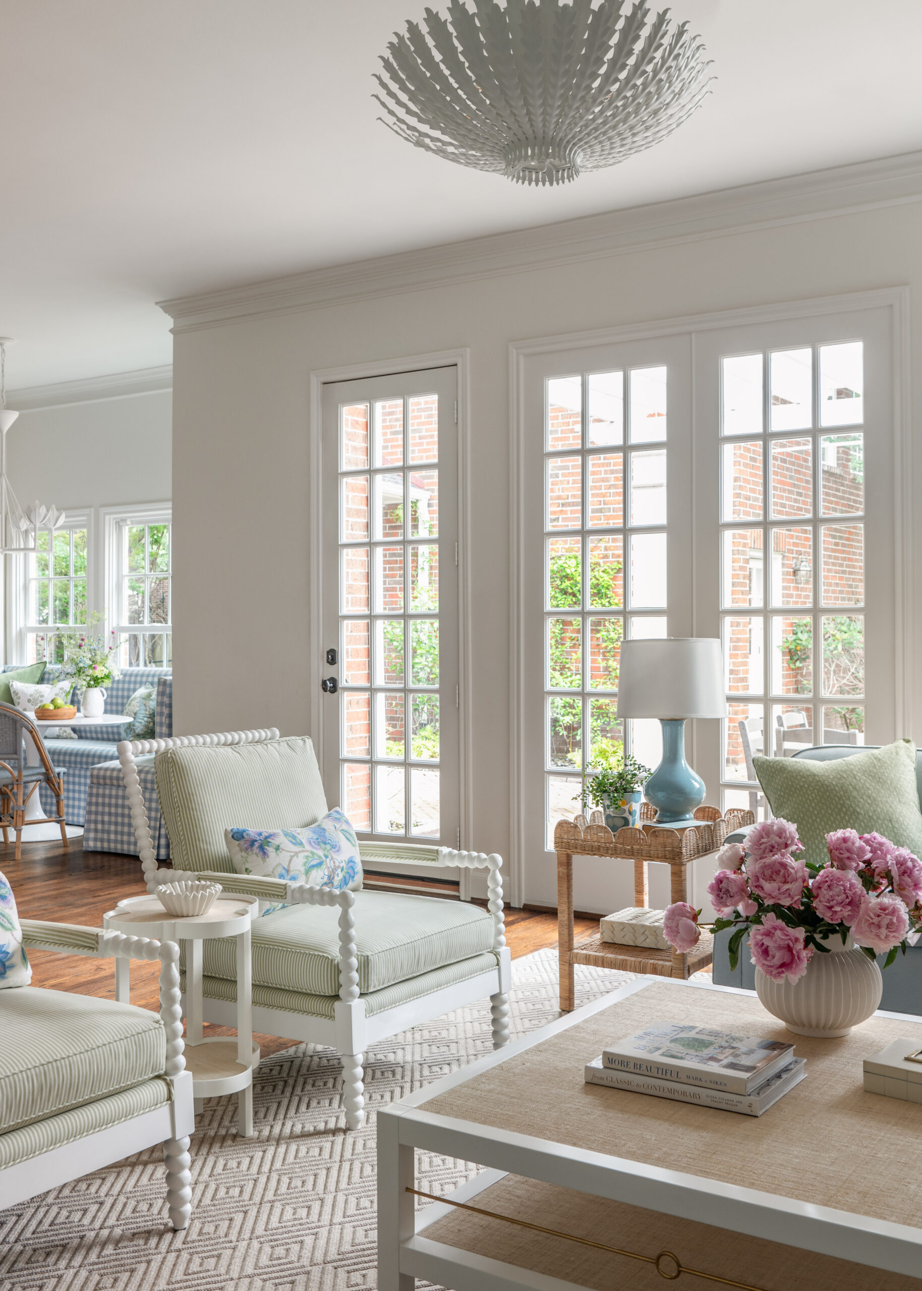 A light and airy living room with classic decor and pastel accents: This spacious living room is filled with natural light from tall windows. The room is adorned with soft blue sofas, white spindle chairs, and floral arrangements, exuding a calming and sophisticated aesthetic.