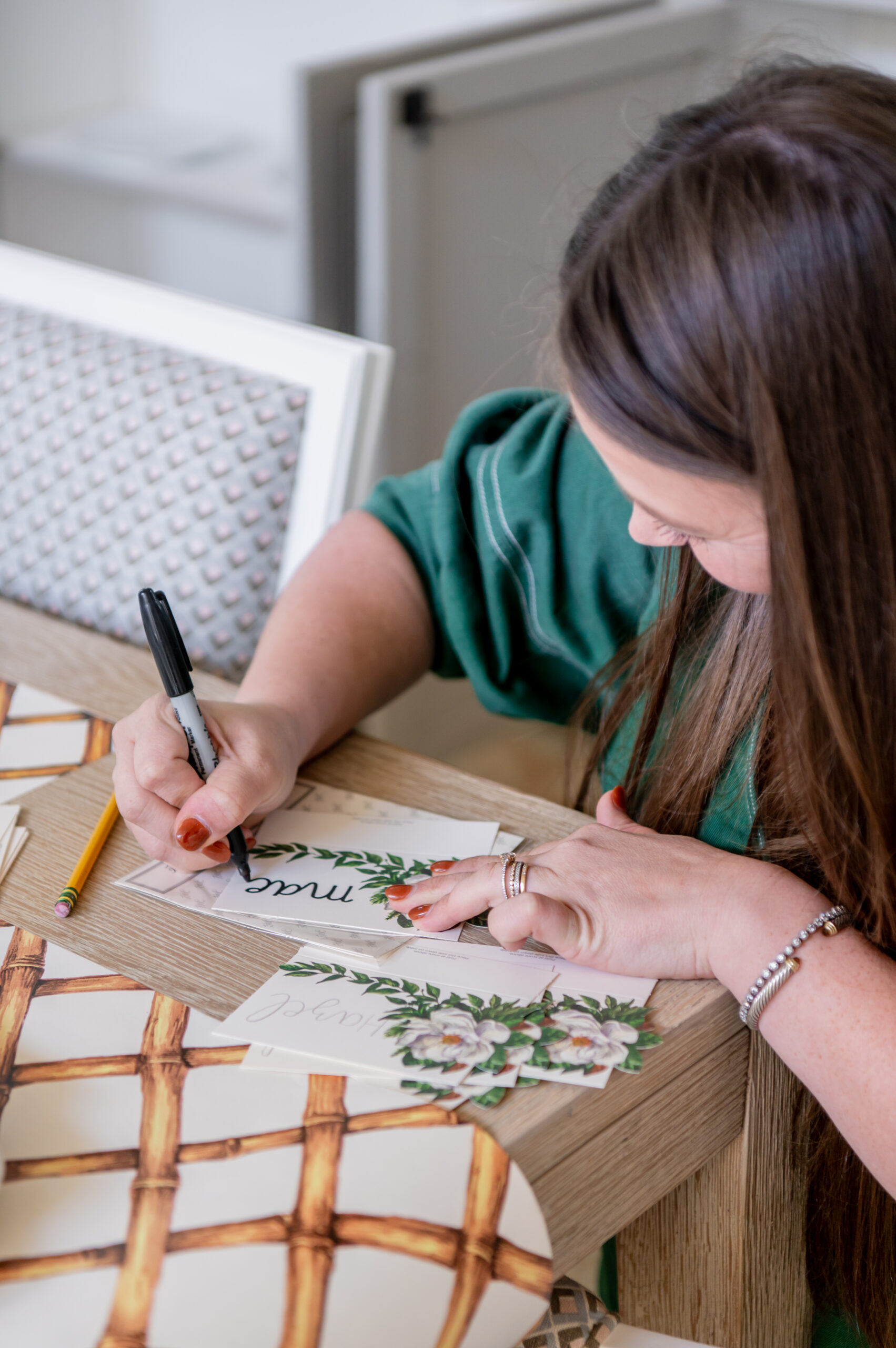 A close-up of a woman writing place cards for a holiday dinner, showcasing the personal touch in seasonal interior design with elegant holiday decorations and festive accents.