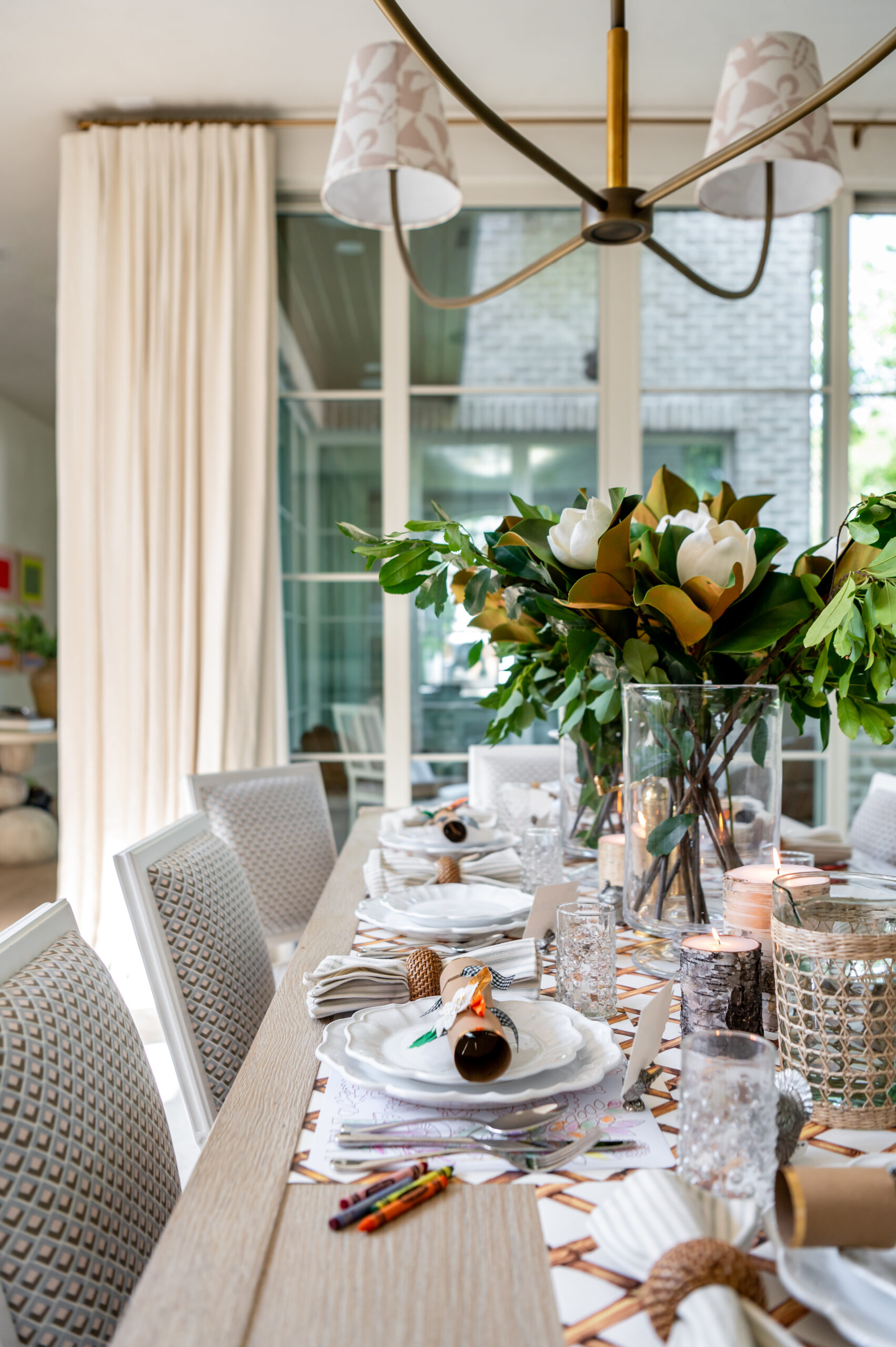 A spacious dining area with a stunning seasonal interior design, featuring elegant magnolia flower arrangements, candles, and a carefully set table for a festive celebration.