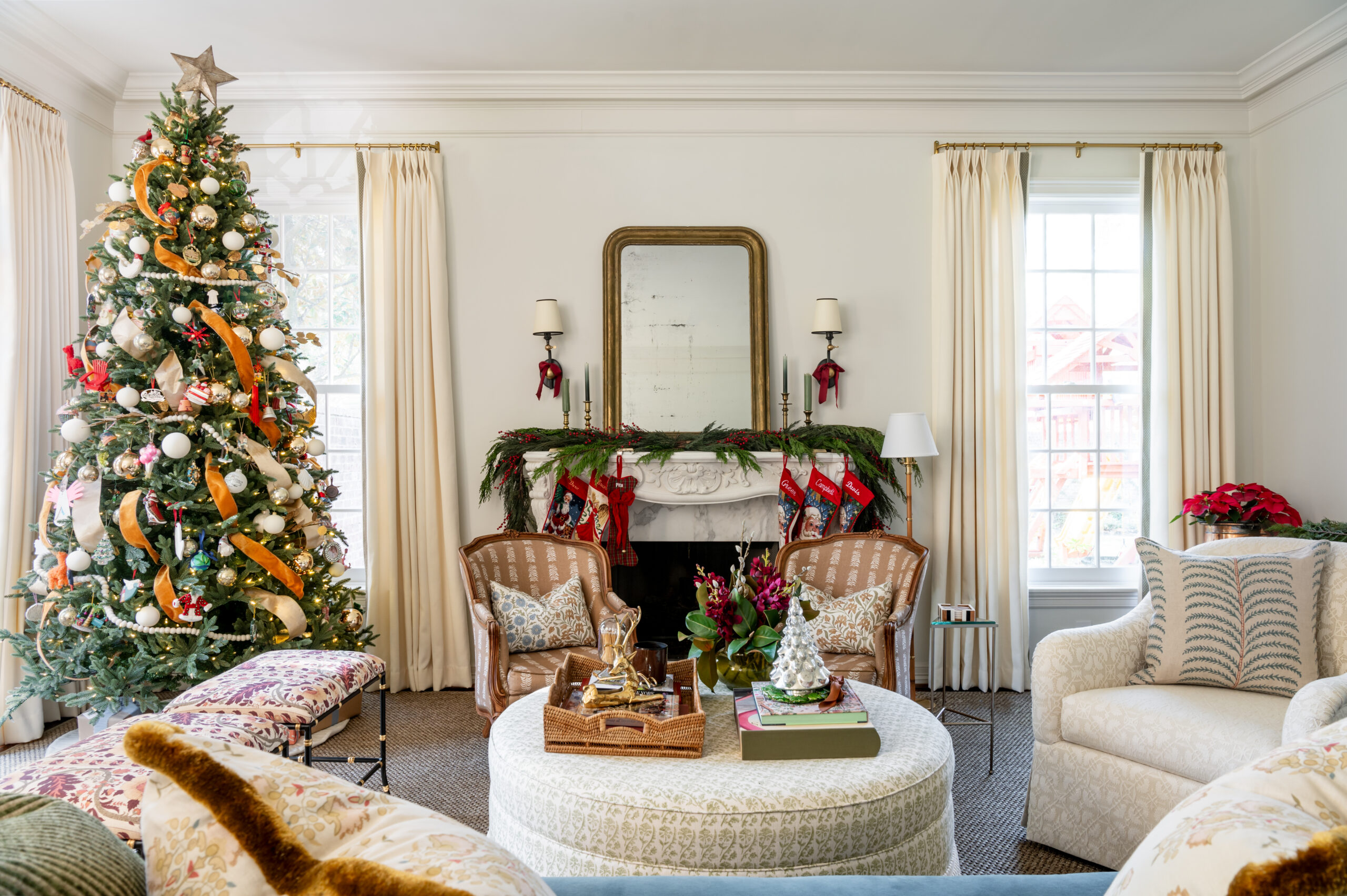 A beautifully decorated living room showcasing a Christmas tree and seasonal interior design, with elegant ribbon and ornaments, stockings hung by the fireplace, and festive floral arrangements