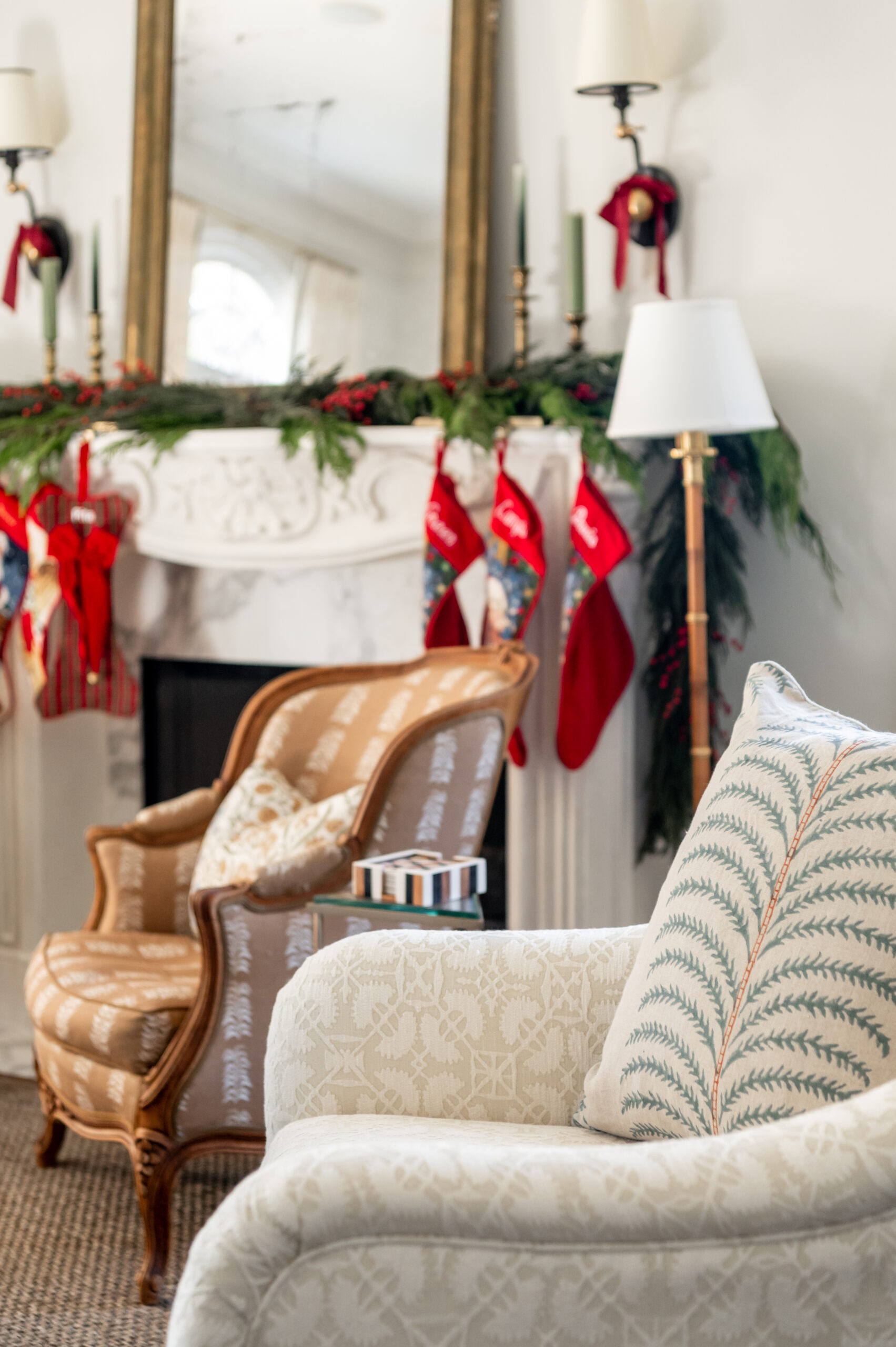 A cozy living room corner with a decorated mantel, stockings, and a beautifully arranged chair, all showcasing seasonal interior design that captures the spirit of the holidays