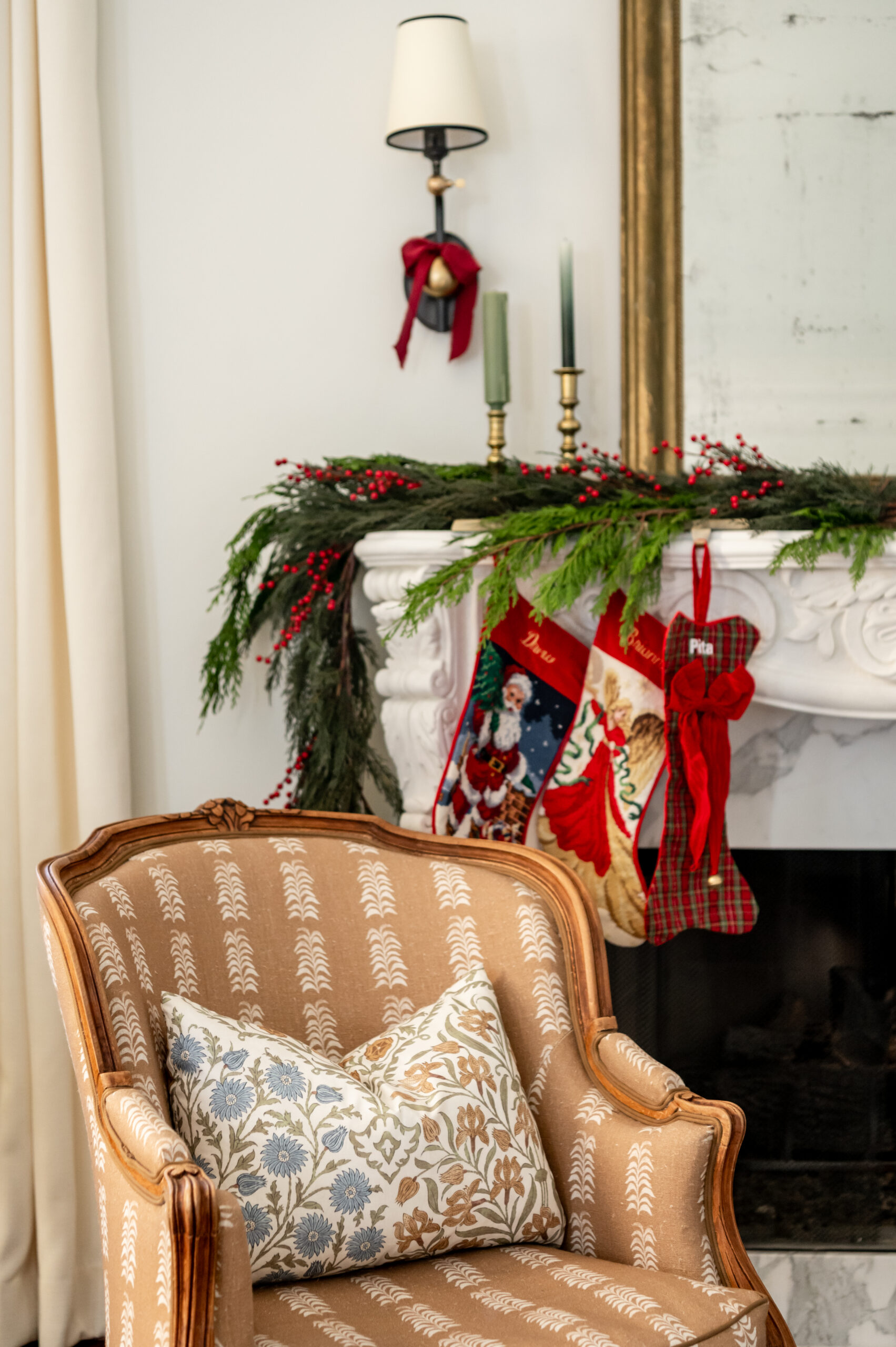 A close-up of a cozy armchair with festive pillows, seasonal interior design touches like a fireplace mantel adorned with stockings, and red and green accents evoking a holiday spirit.