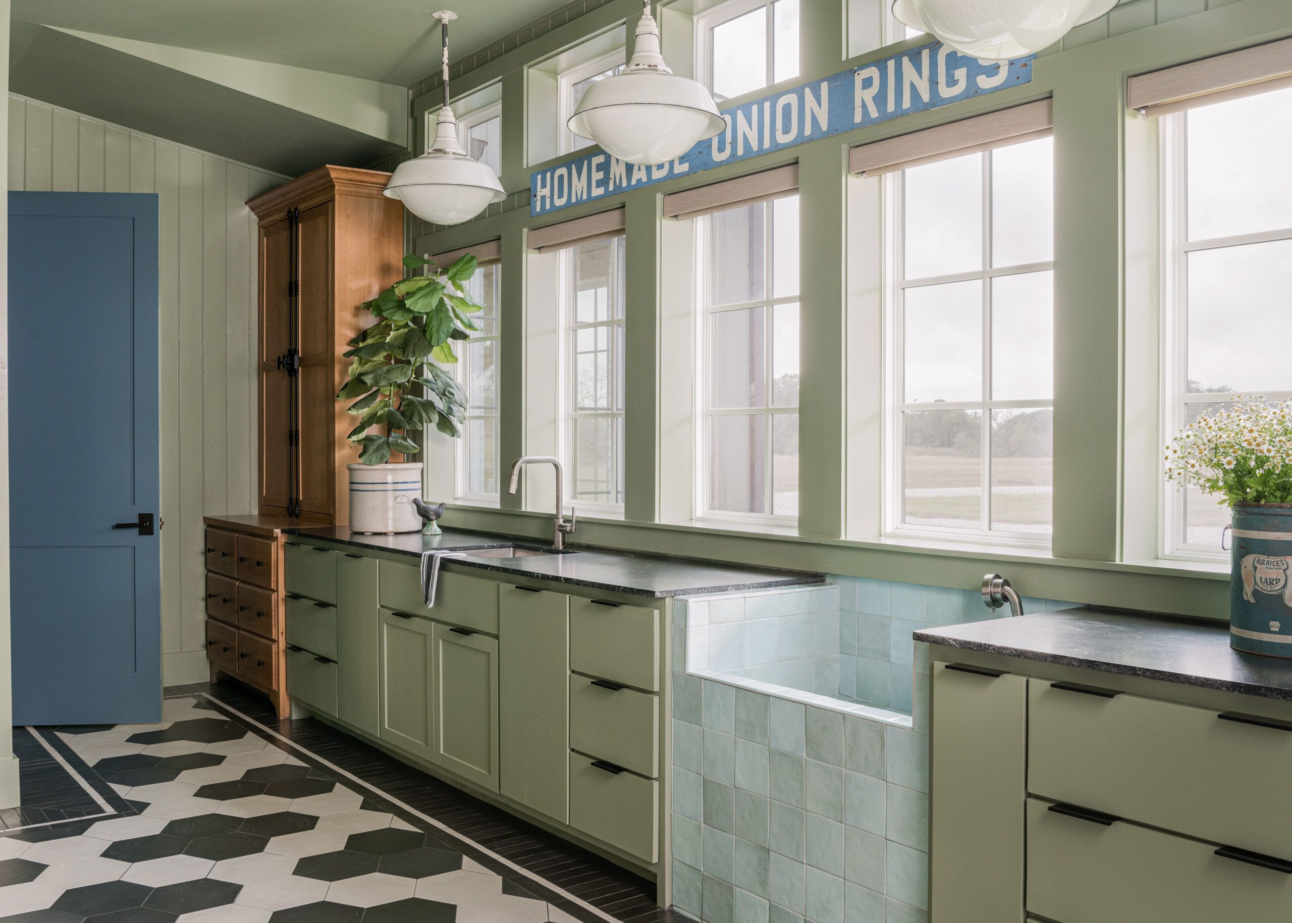 Custom kitchen design with large windows and green cabinetry, showcasing a spacious and inviting atmosphere for a luxurious custom interior design style.