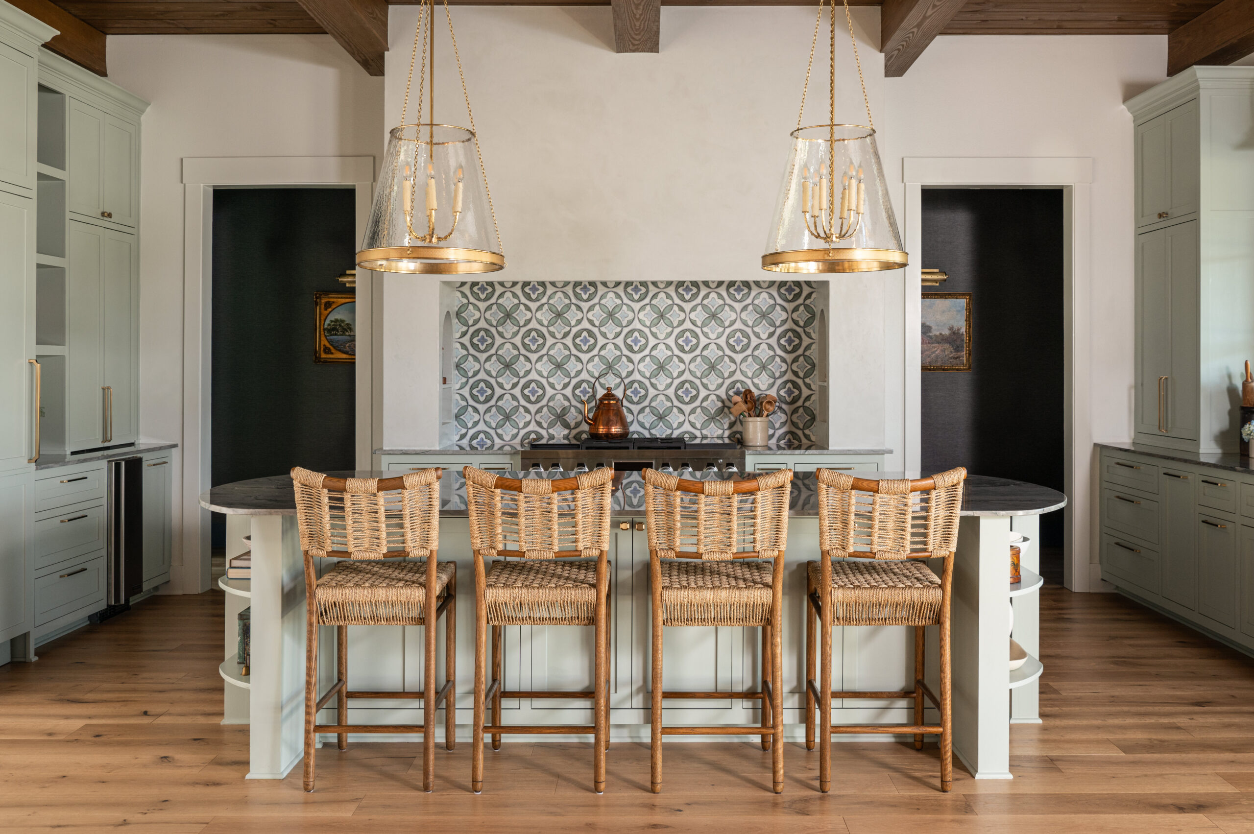 Modern kitchen with custom interior design, featuring woven bar stools, a patterned backsplash, and an elegant pendant light.