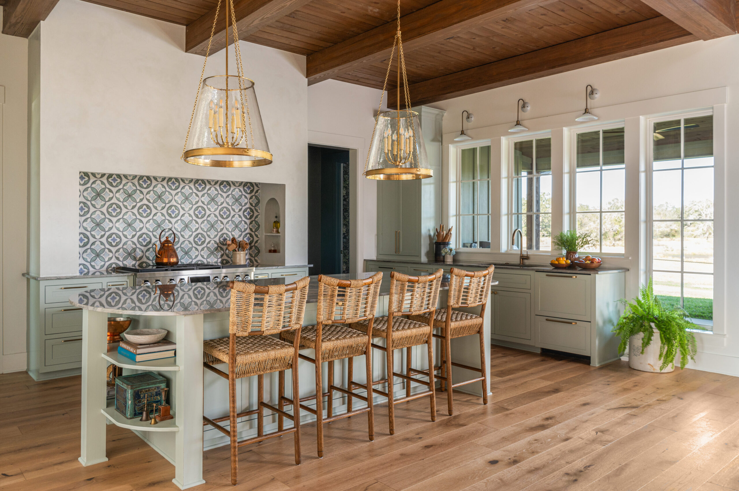 Modern kitchen with custom interior design, featuring woven bar stools, a patterned backsplash, and an elegant pendant light.