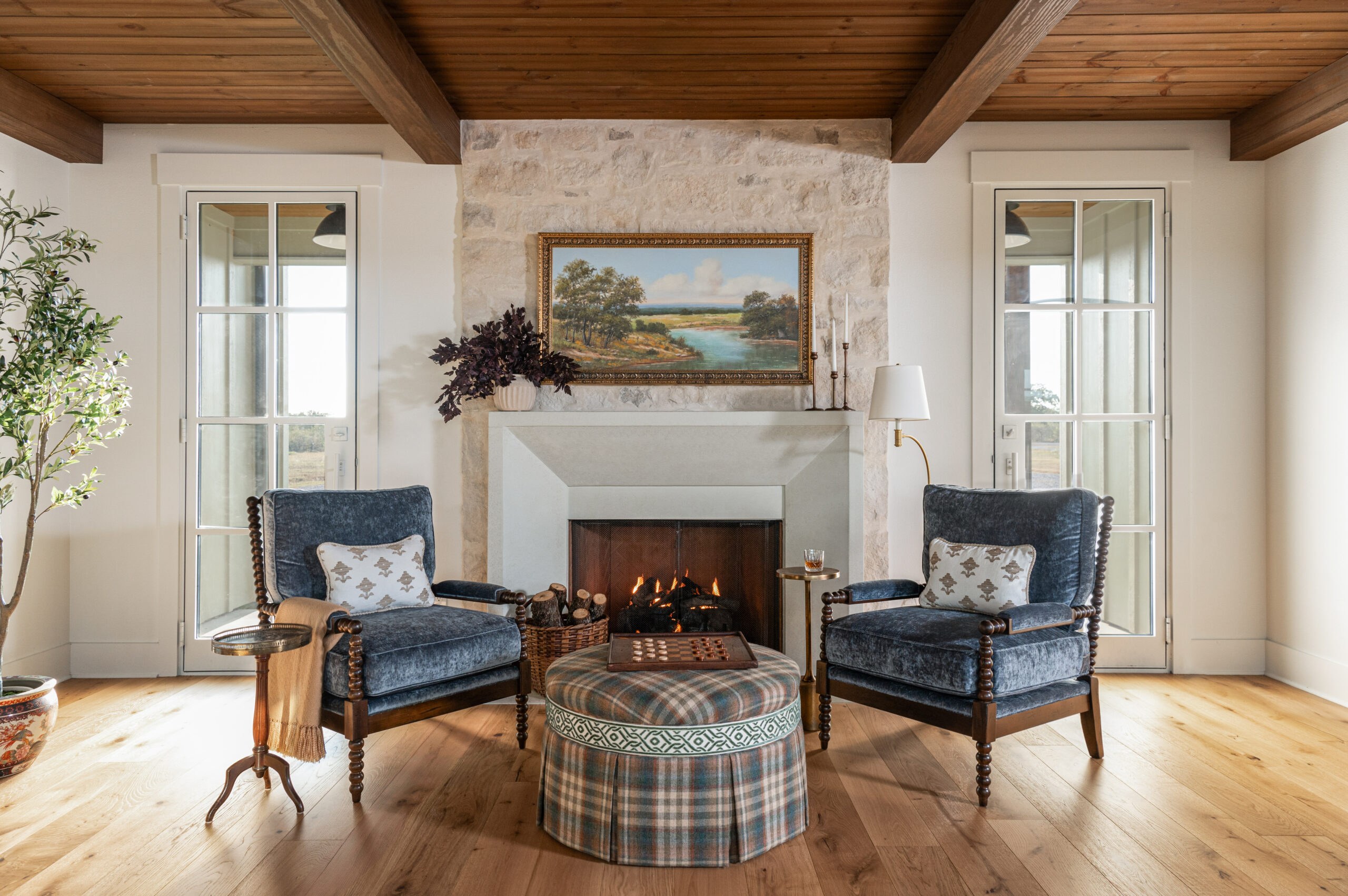 Cozy fireplace nook with custom interior design touches, featuring a vintage painting above the mantle and a comfortable chair.