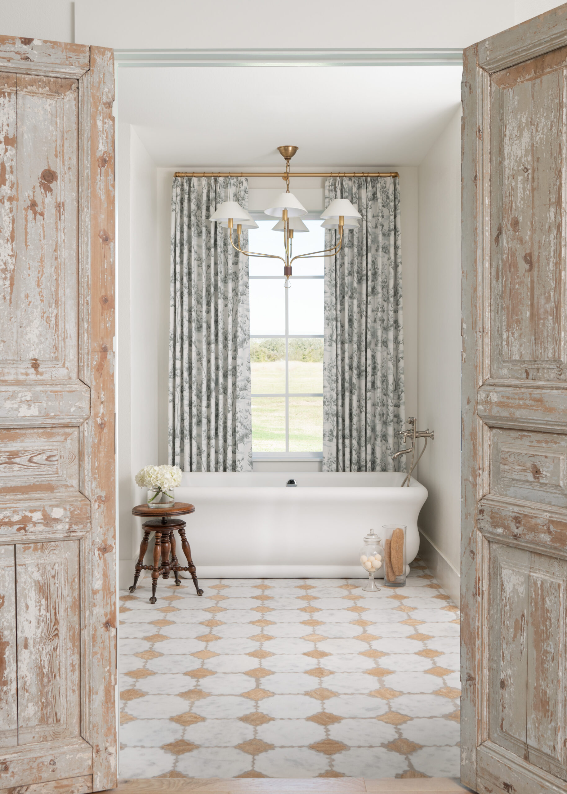 Custom interior design bathroom with a freestanding tub, vintage-inspired tiles, and natural light flowing through the windows.