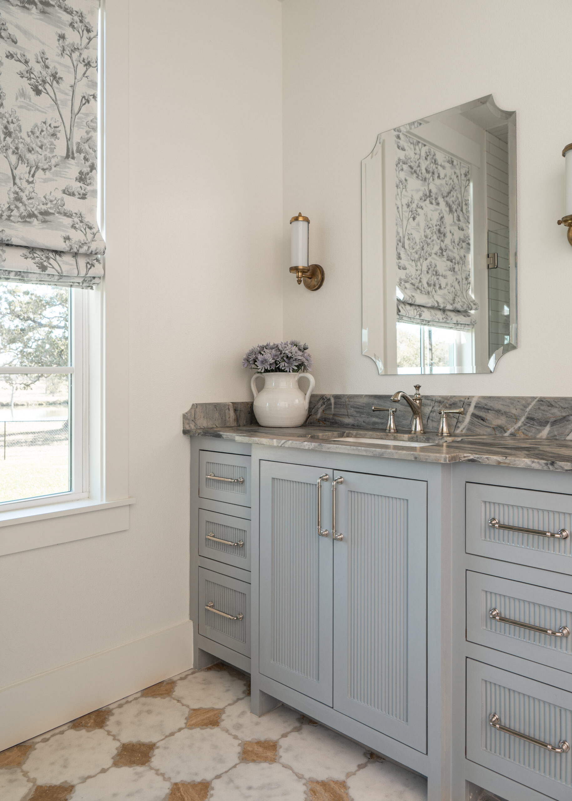 Elegant bathroom vanity area featuring custom interior design with marble countertops, chic light fixtures, and beautiful flowers.