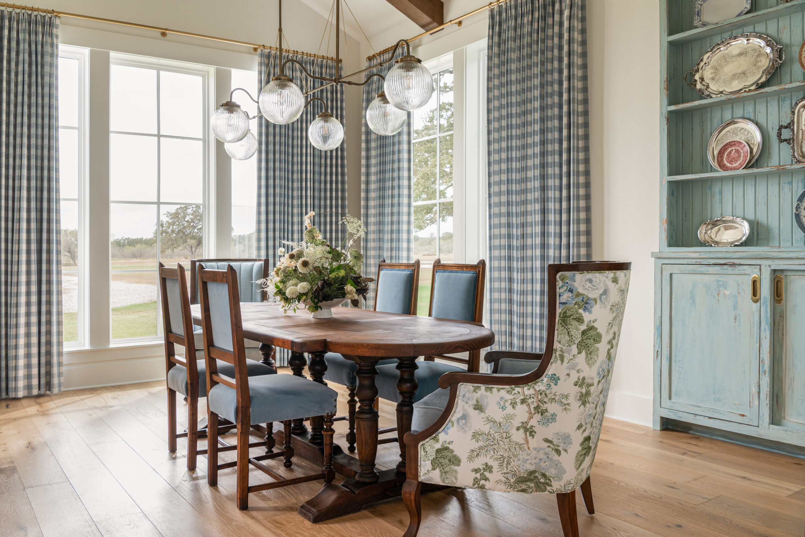 Bright dining area with floral decor, vintage style chairs, and contemporary lighting, highlighting the perfect balance of custom interior design and style.