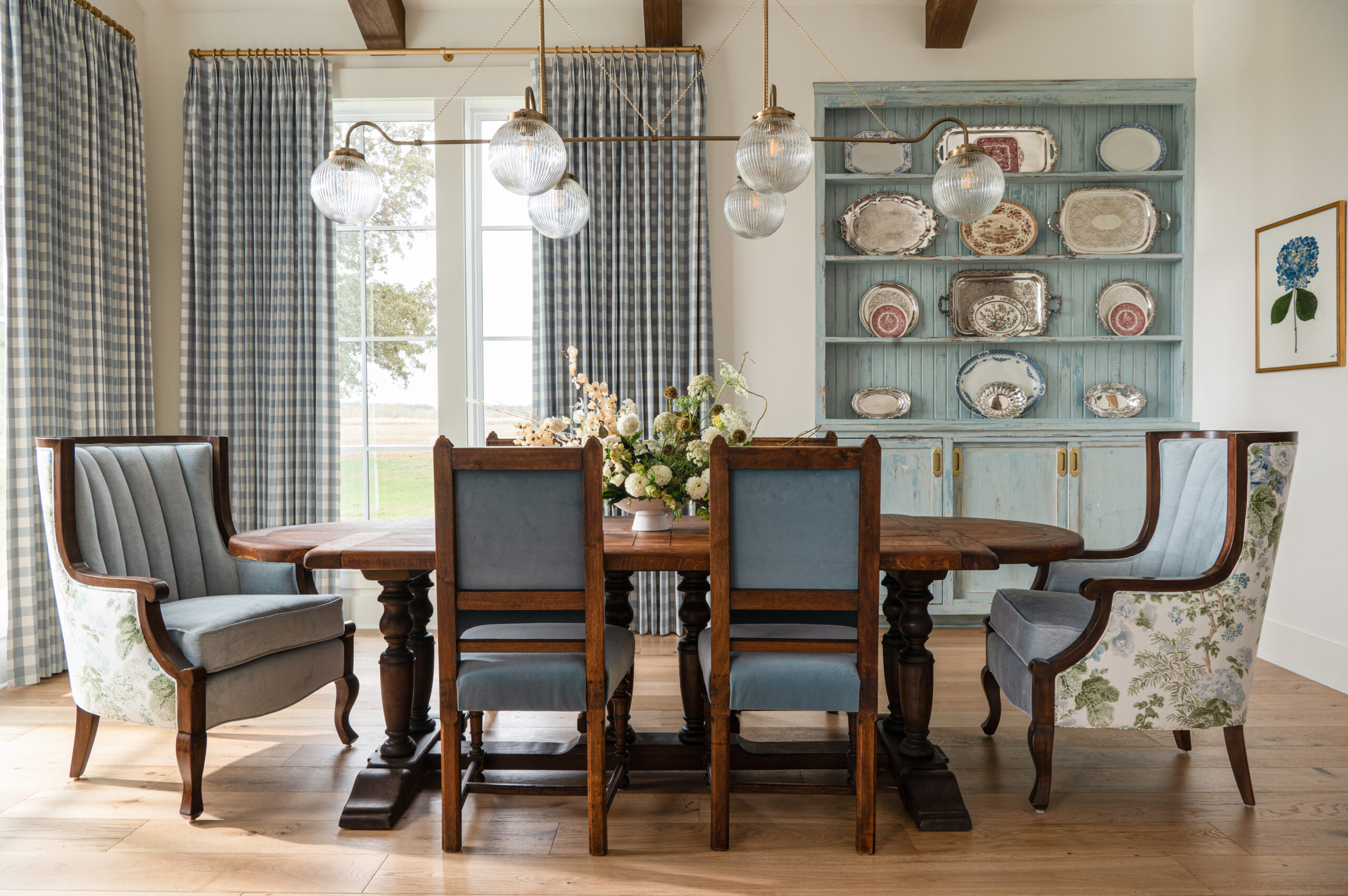 Bright dining area with floral decor, vintage style chairs, and contemporary lighting, highlighting the perfect balance of custom interior design and style.