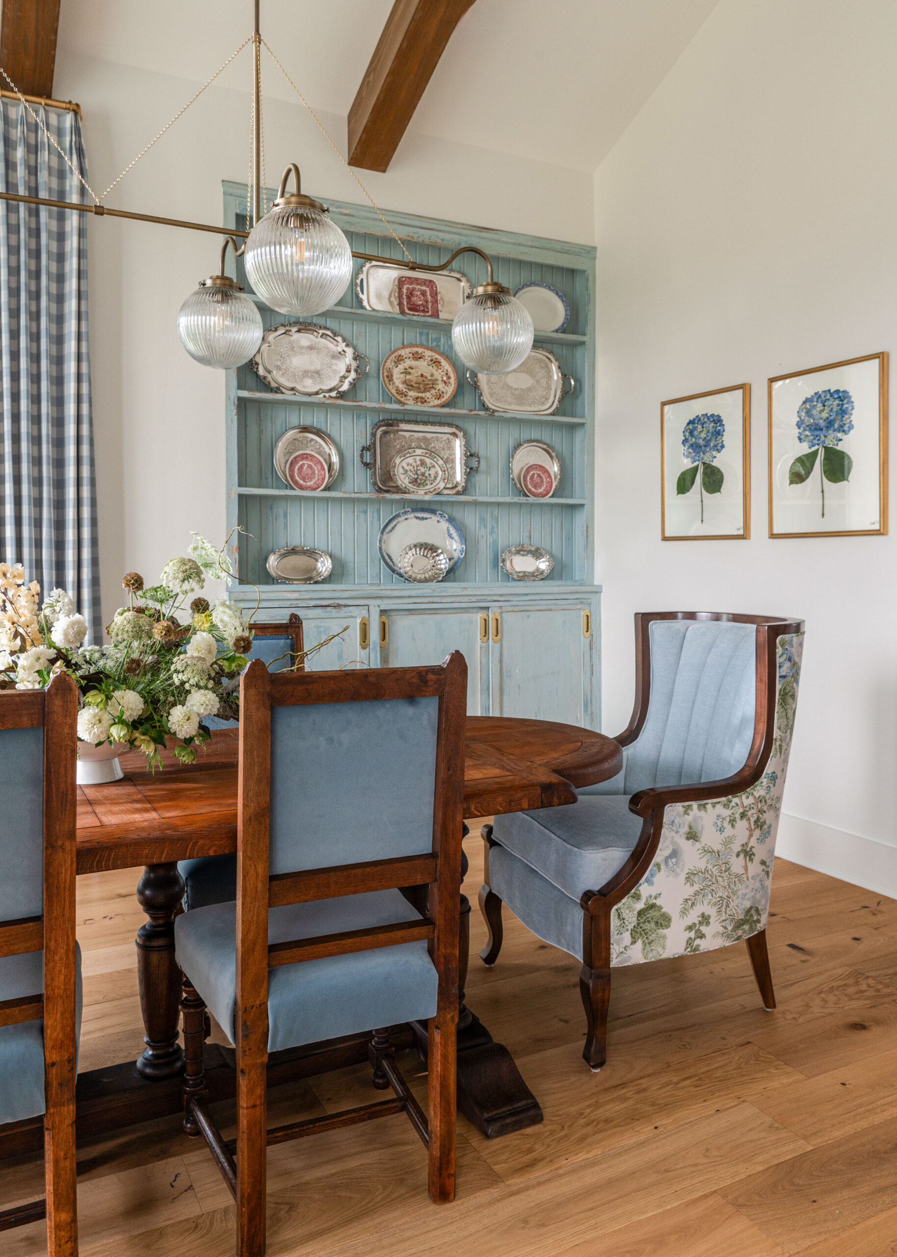 Bright dining area with floral decor, vintage style chairs, and contemporary lighting, highlighting the perfect balance of custom interior design and style.