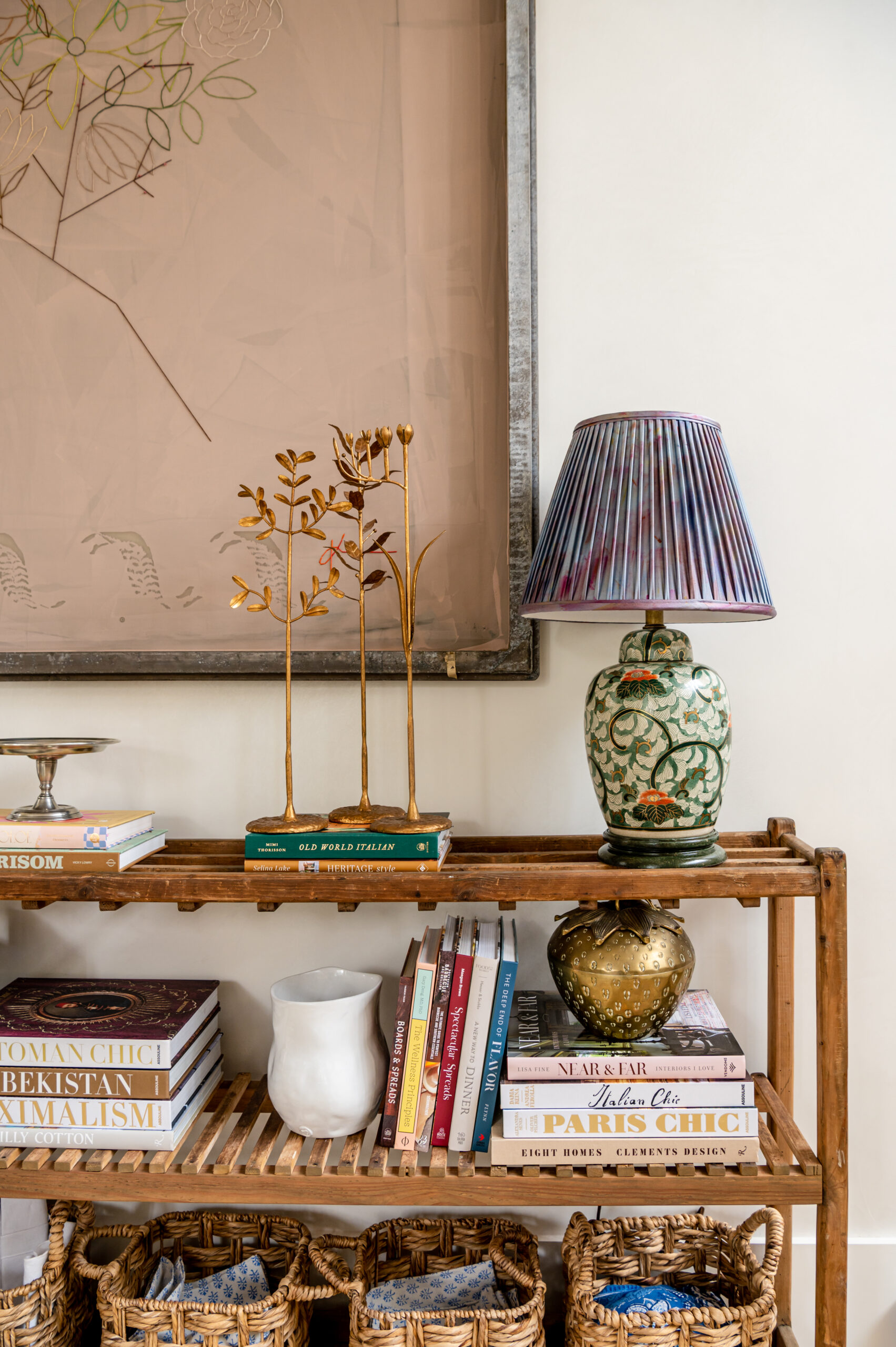 An eclectic shelf featuring books, decorative objects, and a pair of striking lamps. This combination of modern and classic design elements highlights the seamless blending of styles typical of a master interior design approach