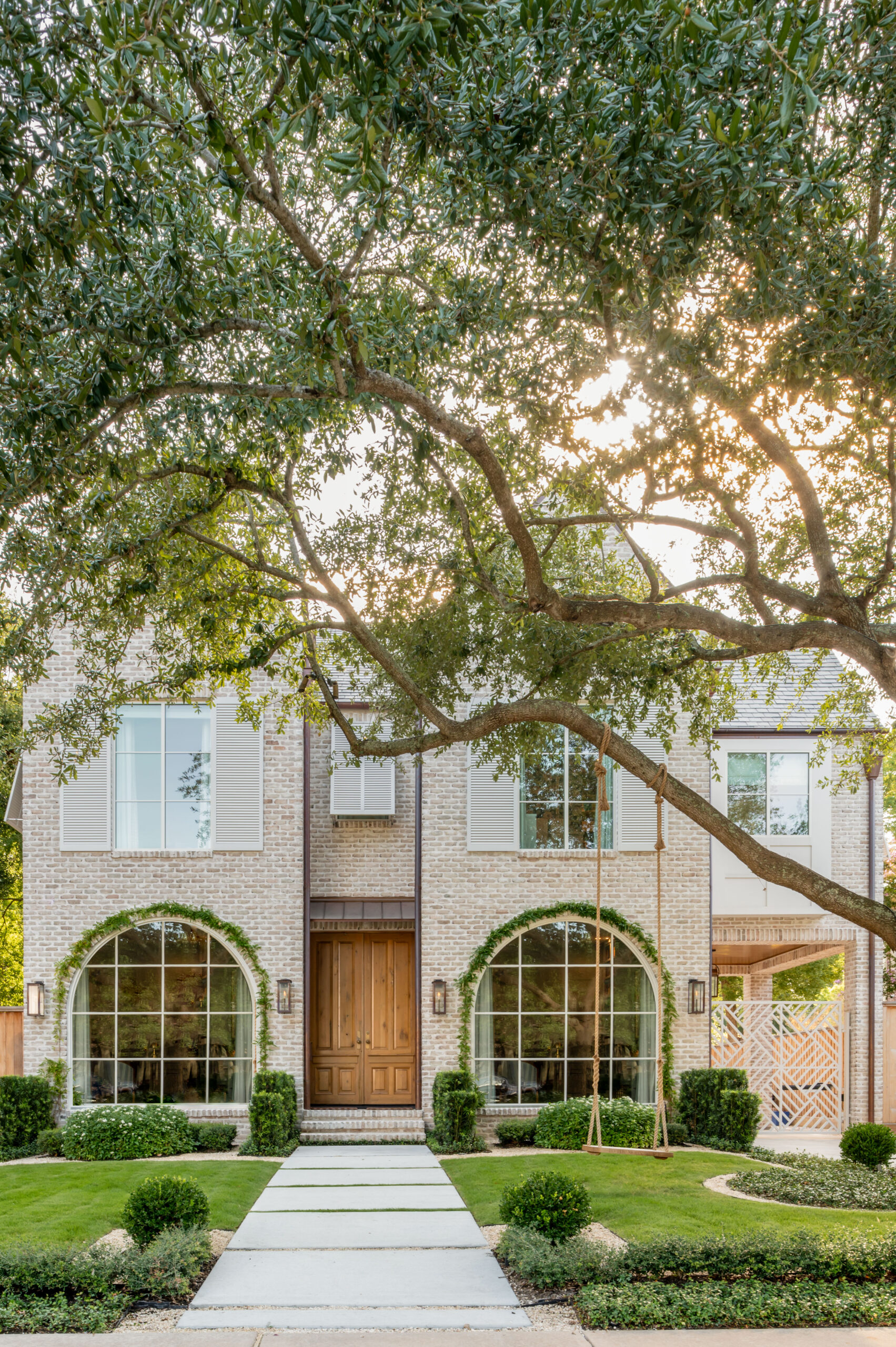 A beautiful brick home with lush greenery and large windows, showcasing master interior design with a seamless transition between the outdoor and indoor spaces.