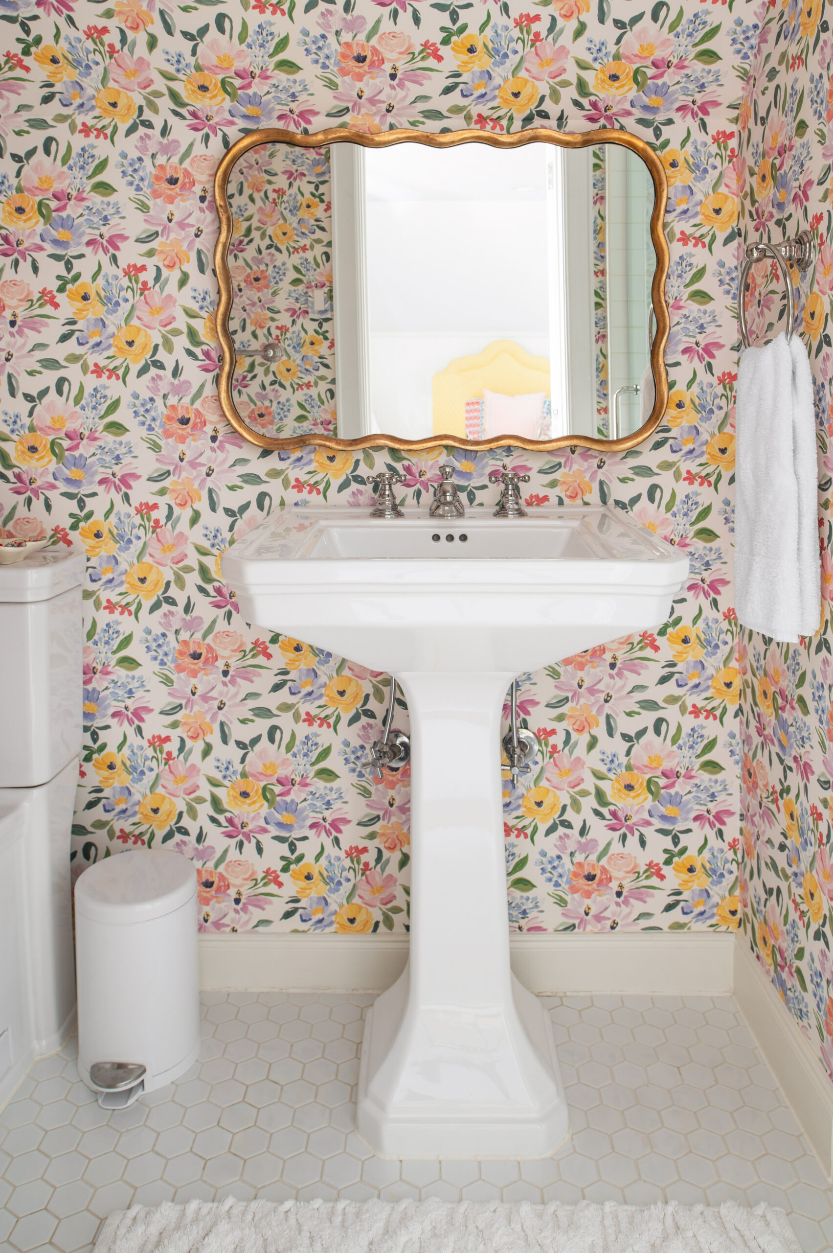 A lively bathroom with bright floral wallpaper and a gold-framed mirror, reflecting a youthful and vibrant design aesthetic that still adheres to the core principles of master interior design.