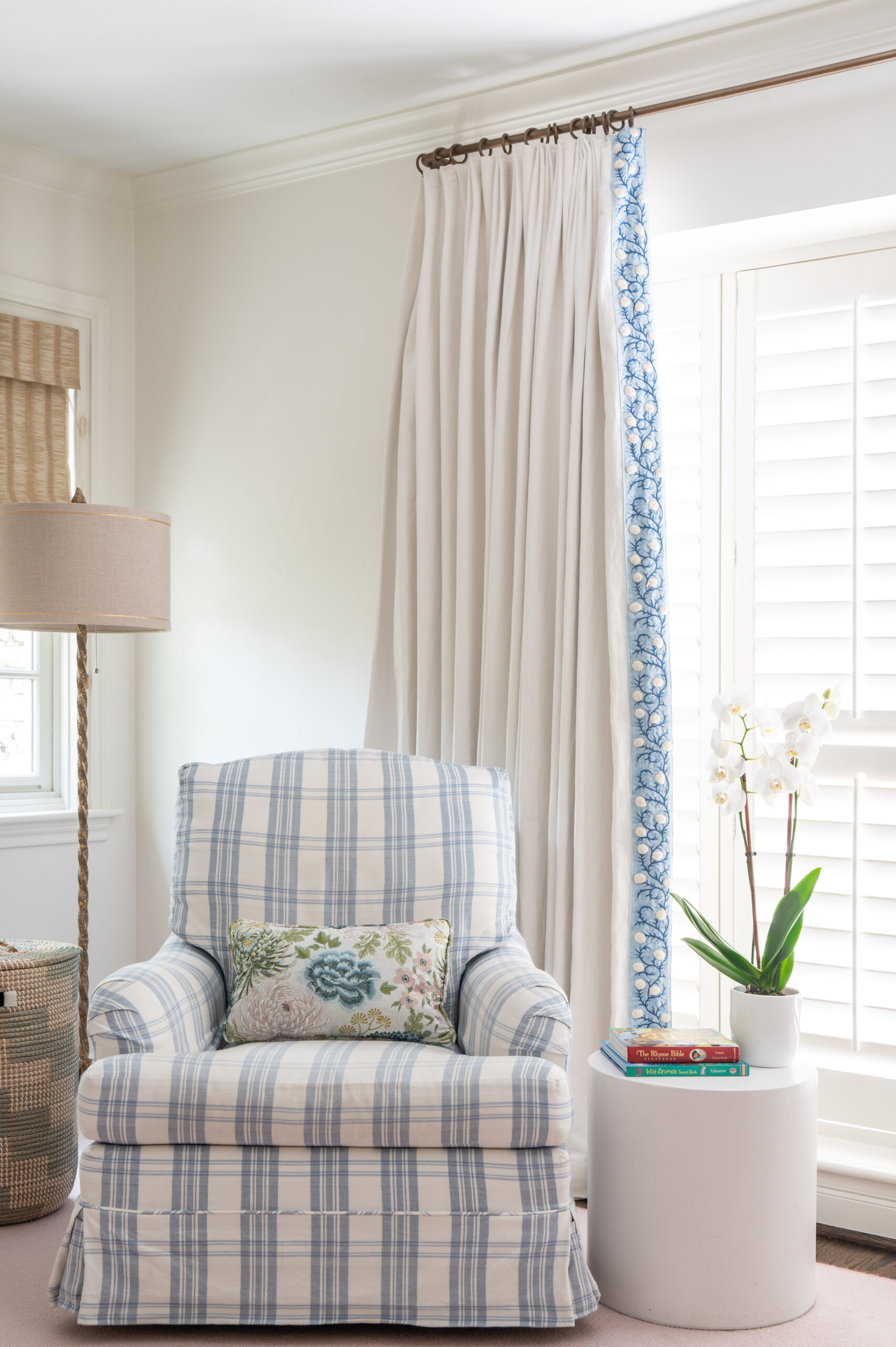 A cozy corner featuring a blue checked armchair, orchids, and natural light, illustrating master interior design through its thoughtful arrangement and combination of textures and colors.