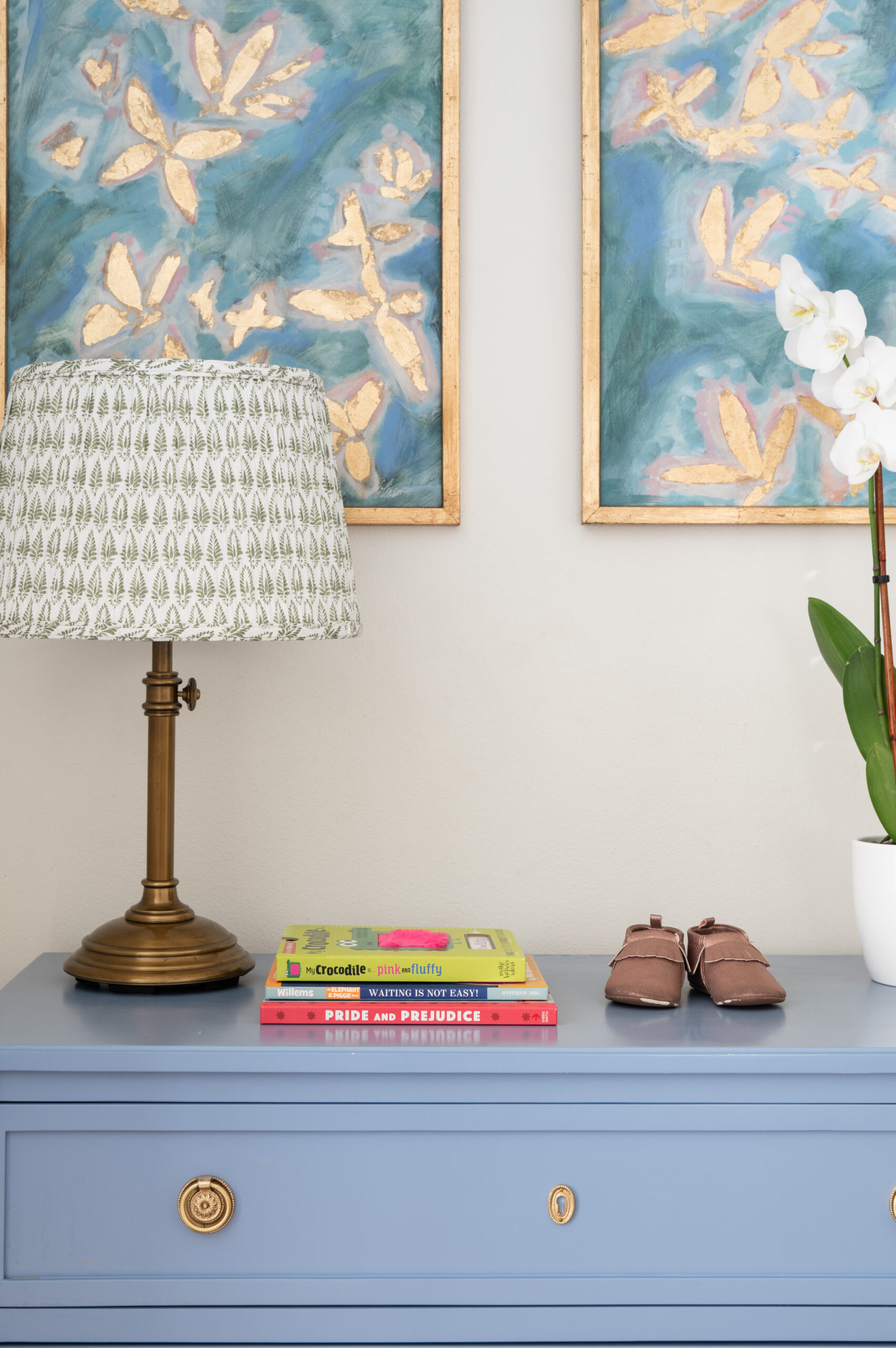 A close-up of an elegant interior with artistic paintings, books, and a lamp showcasing the importance of master interior design in creating personalized, functional spaces.