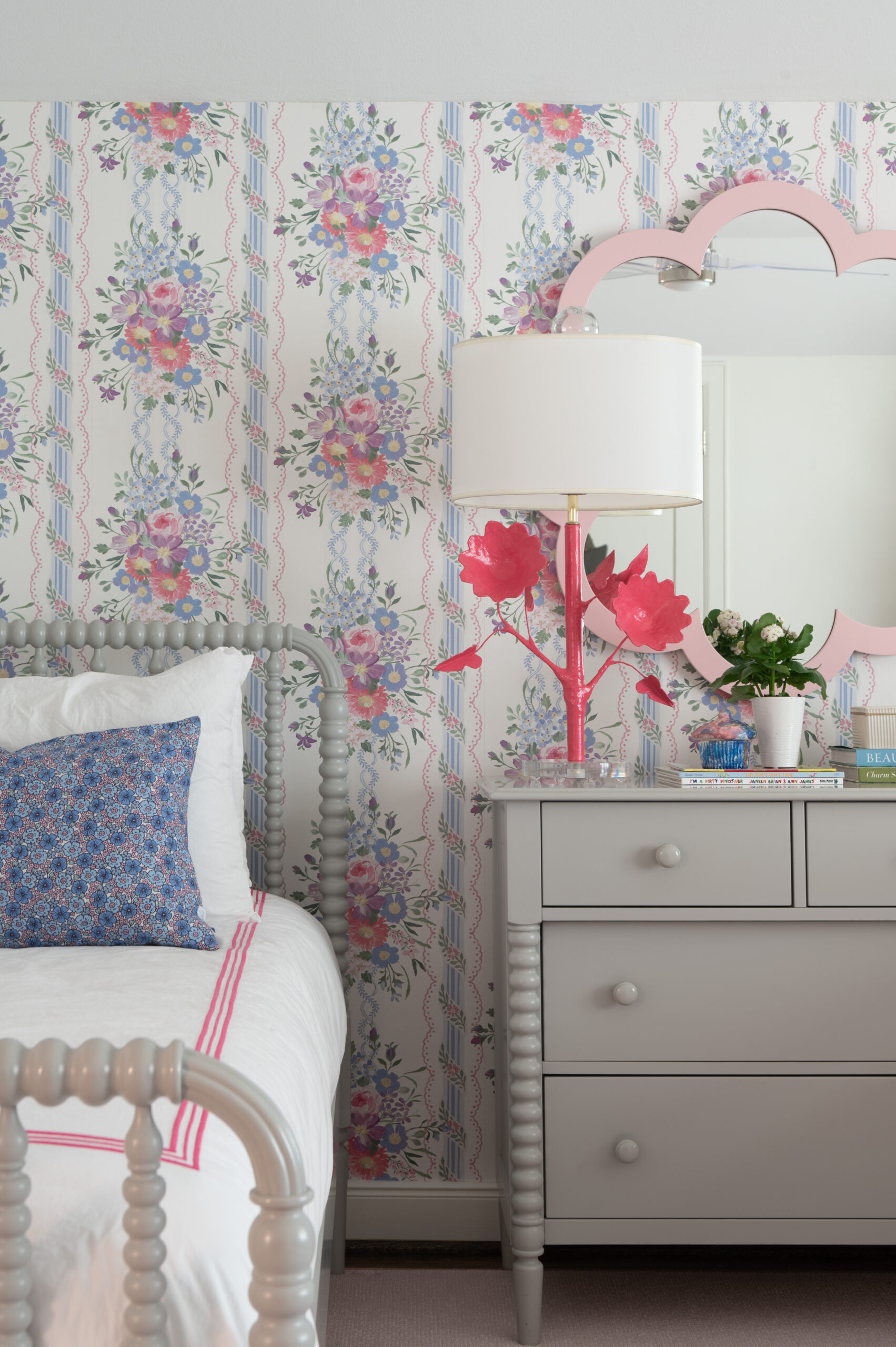 A playful bedroom featuring vibrant floral wallpaper, a pink-framed mirror, and bold-colored accents. This room showcases a fun and eclectic master interior design approach, adding character and warmth.