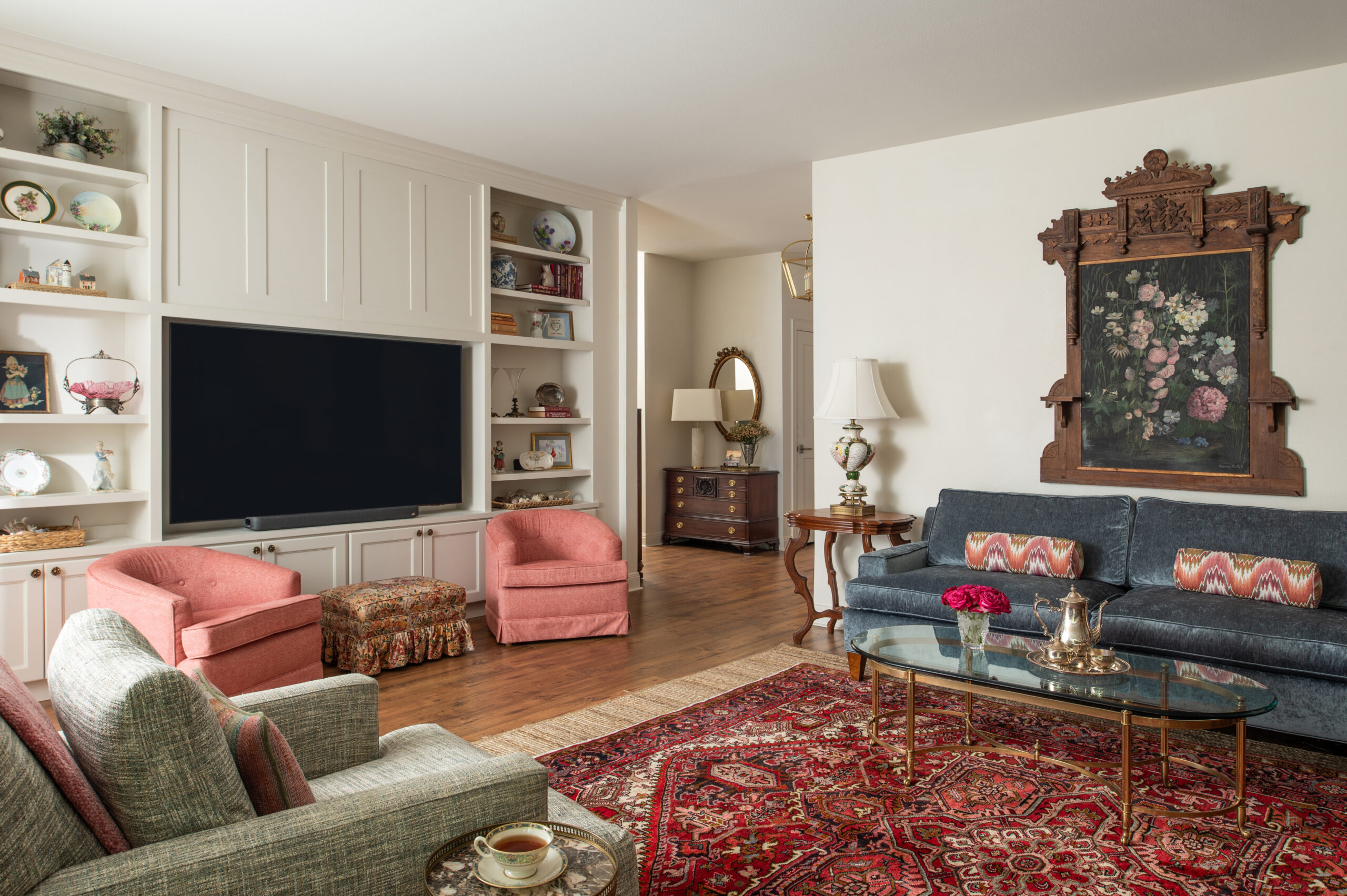 Cozy living room featuring timeless modern interior design with two armchairs, a sofa, and a colorful rug, accented by plants and elegant decor pieces.