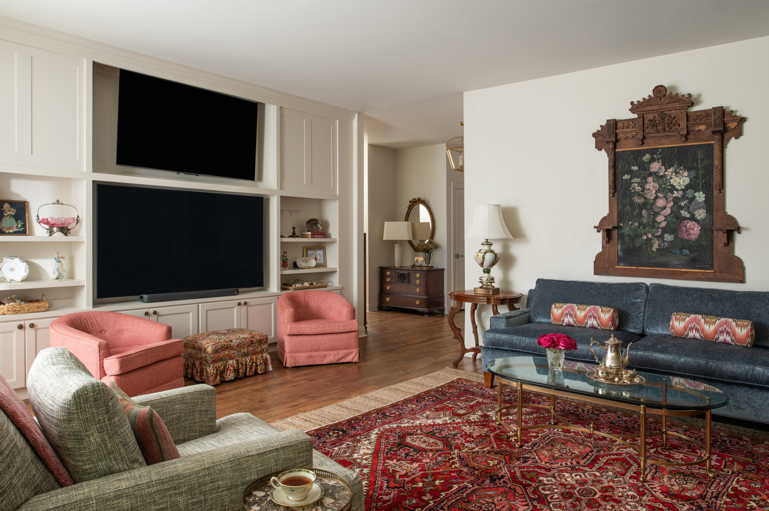 : Another view of a modern living room with a cozy setup, showcasing a glass coffee table, plush seating, and a vintage-style bookshelf, reflecting timeless modern interior design.