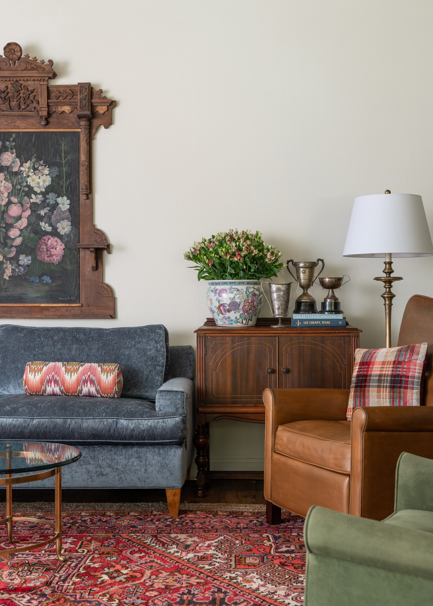 A close-up of the living room, focusing on vintage furniture and decorative items like floral arrangements and trophies, contributing to a timeless modern interior design atmosphere.