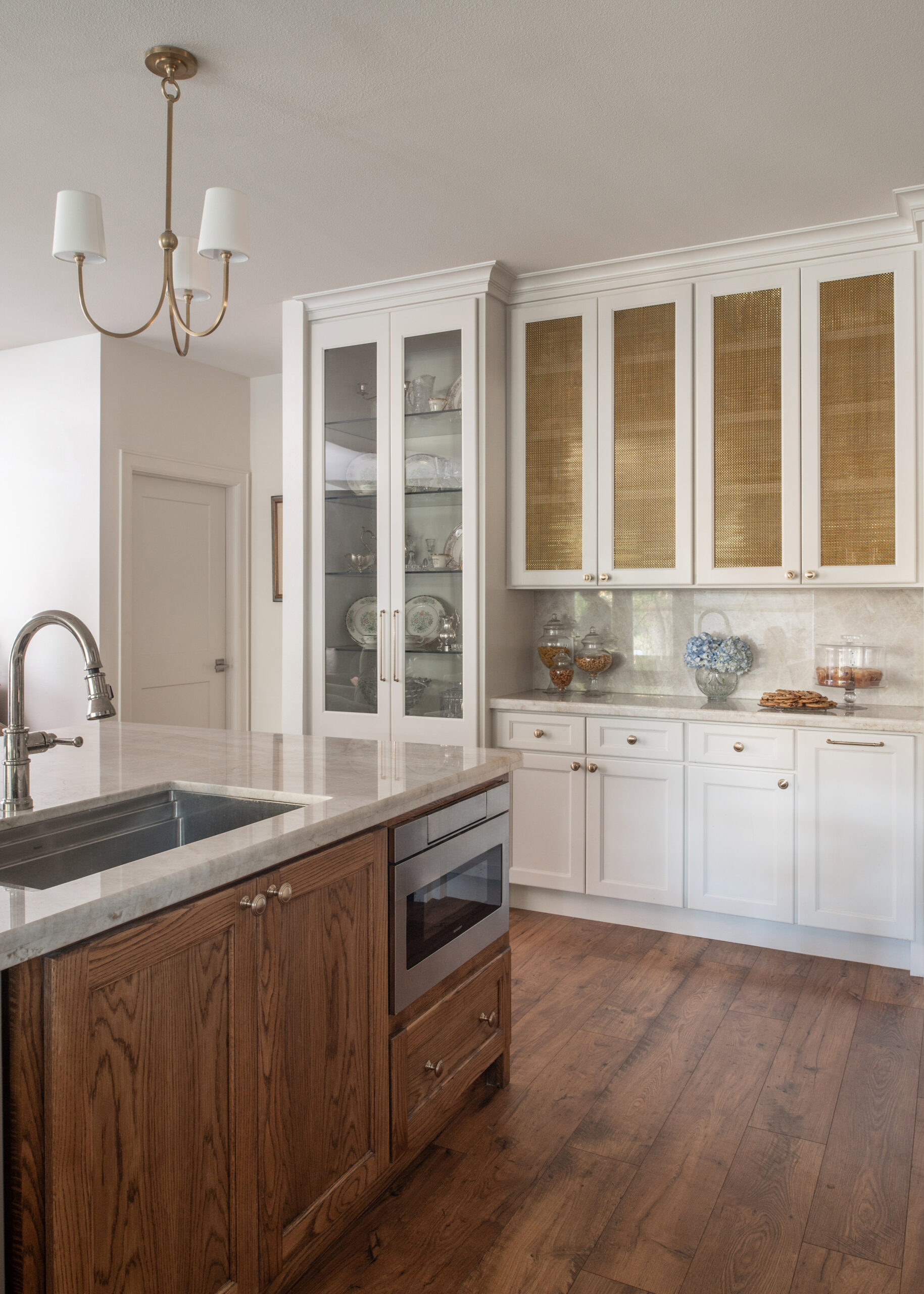 A spacious kitchen featuring a beautifully designed marble countertop and glass cabinets, exuding a timeless modern interior design style with an elegant touch.