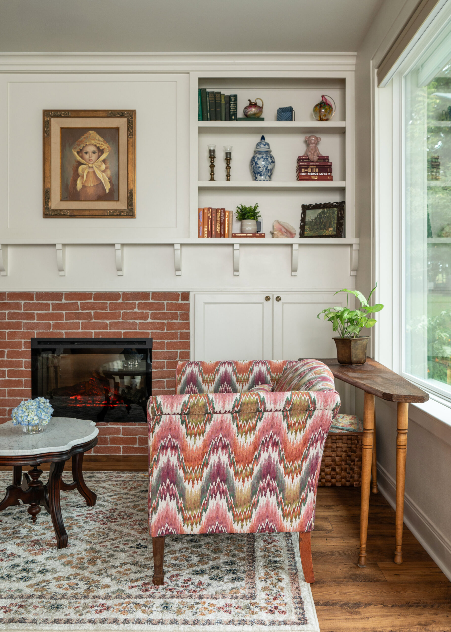 A close-up of a modern seating area by the fireplace, highlighting the eclectic mix of decor, including bookshelves, artwork, and plants. This timeless modern interior design balances comfort and style effortlessly.