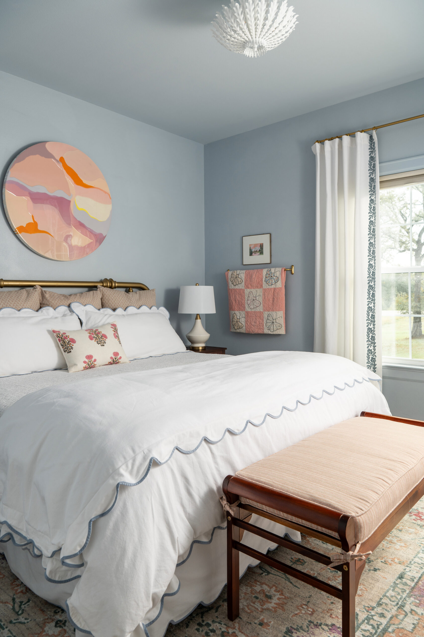 A bright, playful bedroom with a soft blue palette and modern artwork hanging above the bed. This space blends the timeless modern interior design aesthetic with a fresh, youthful touch.