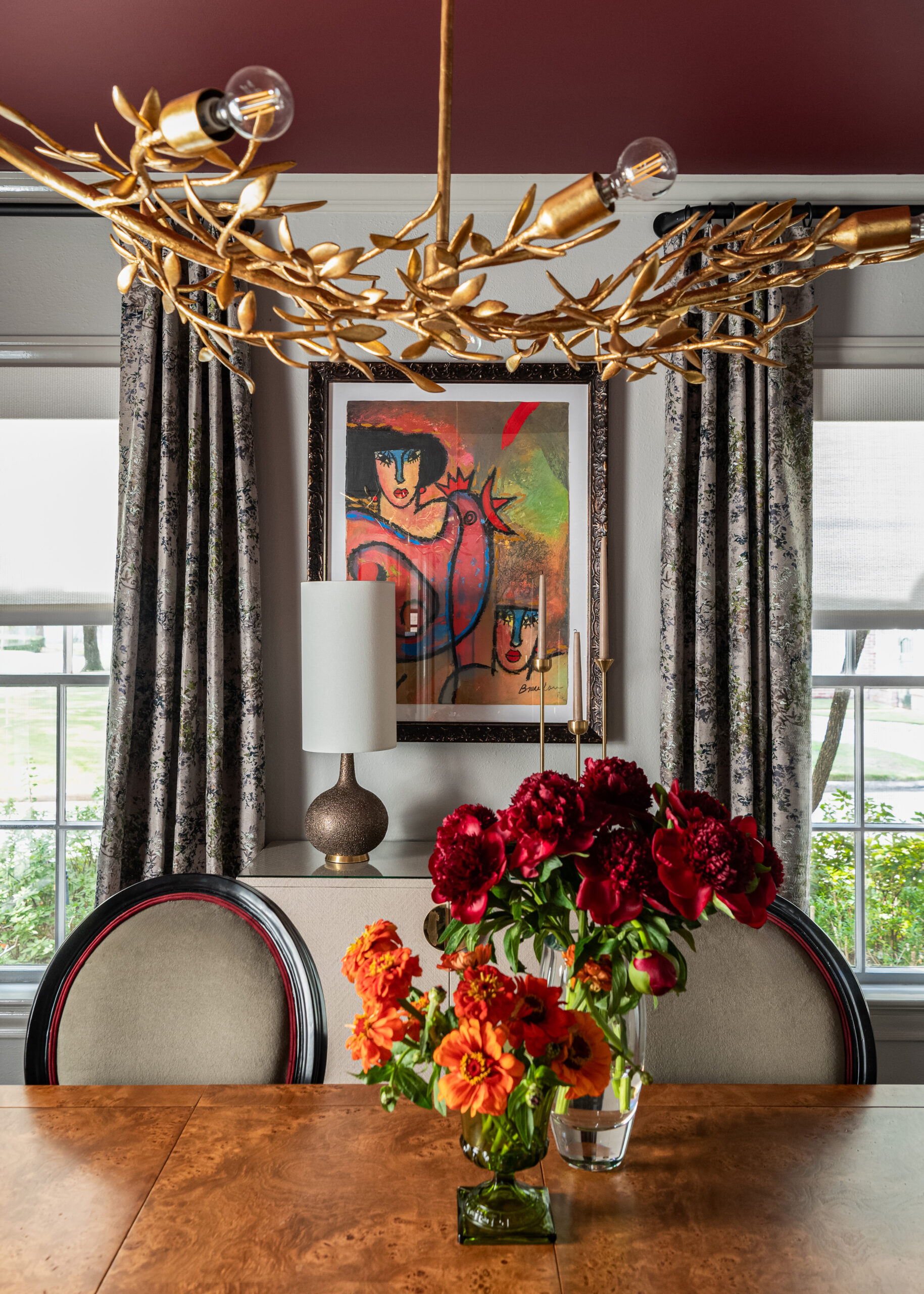 A cozy dining area with stunning floral arrangements and artwork that contrast beautifully with the sleek, traditional furniture.