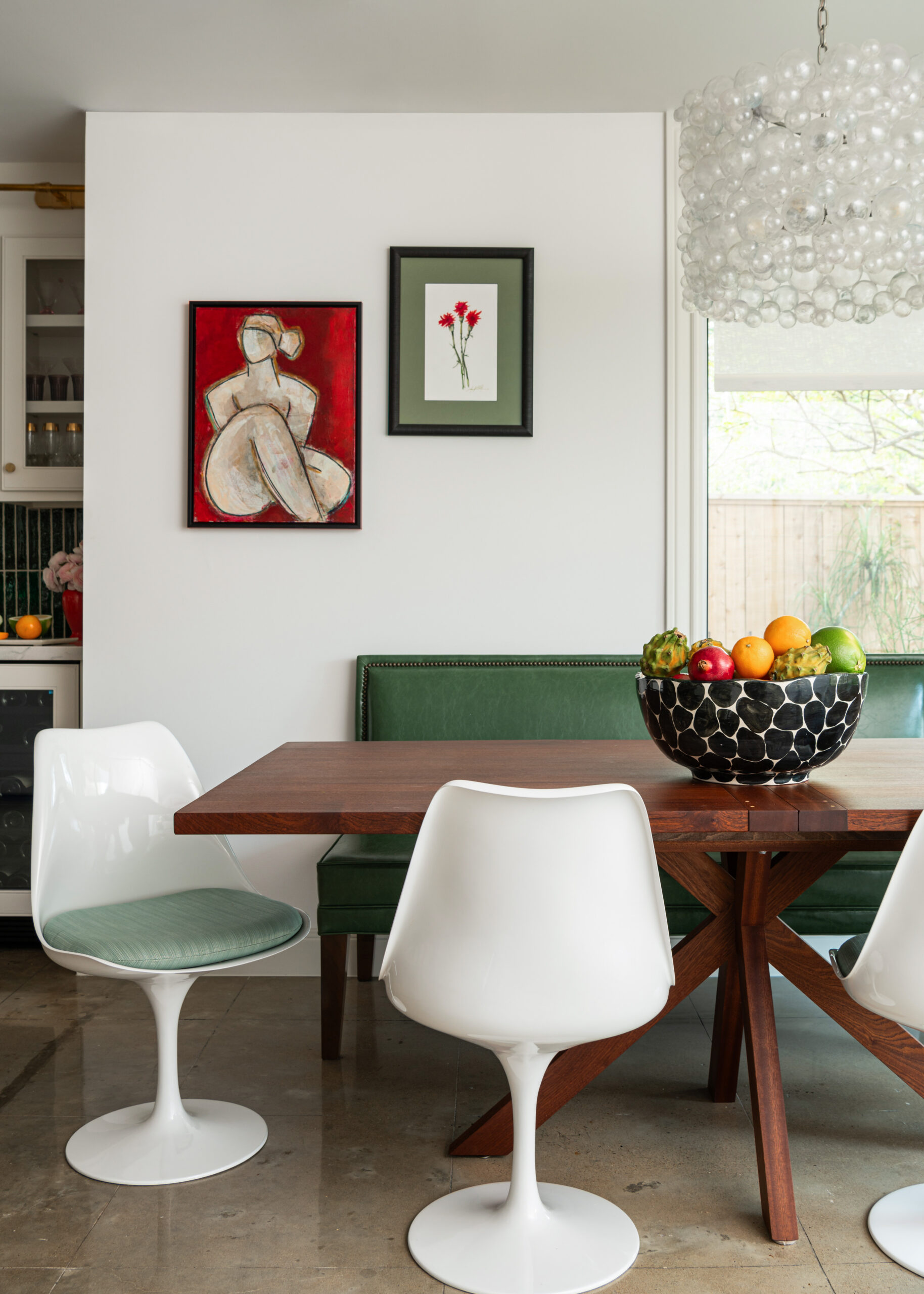 A beautifully styled dining nook with modern art and statement lighting. This interior design photograph emphasizes the striking contrast between modern and classic elements.