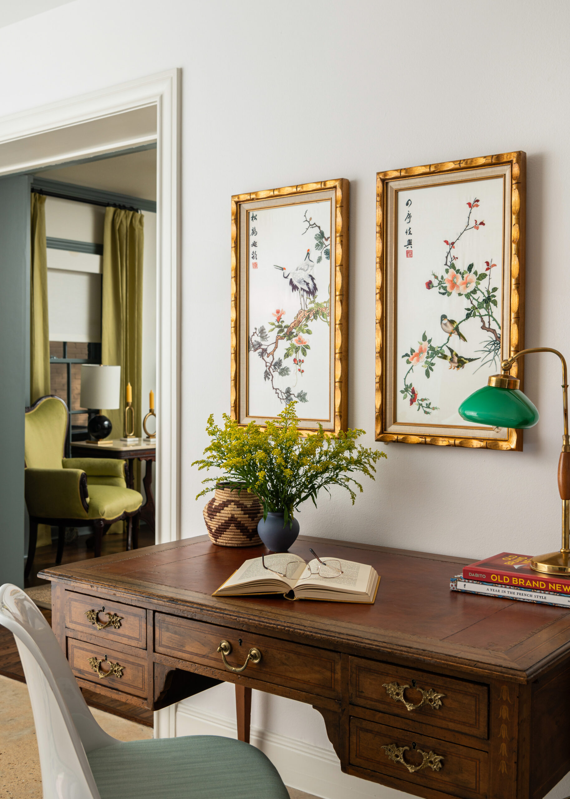 Interior design and photography capture traditional design elements and green hues in a stylish workspace with artwork and plants.