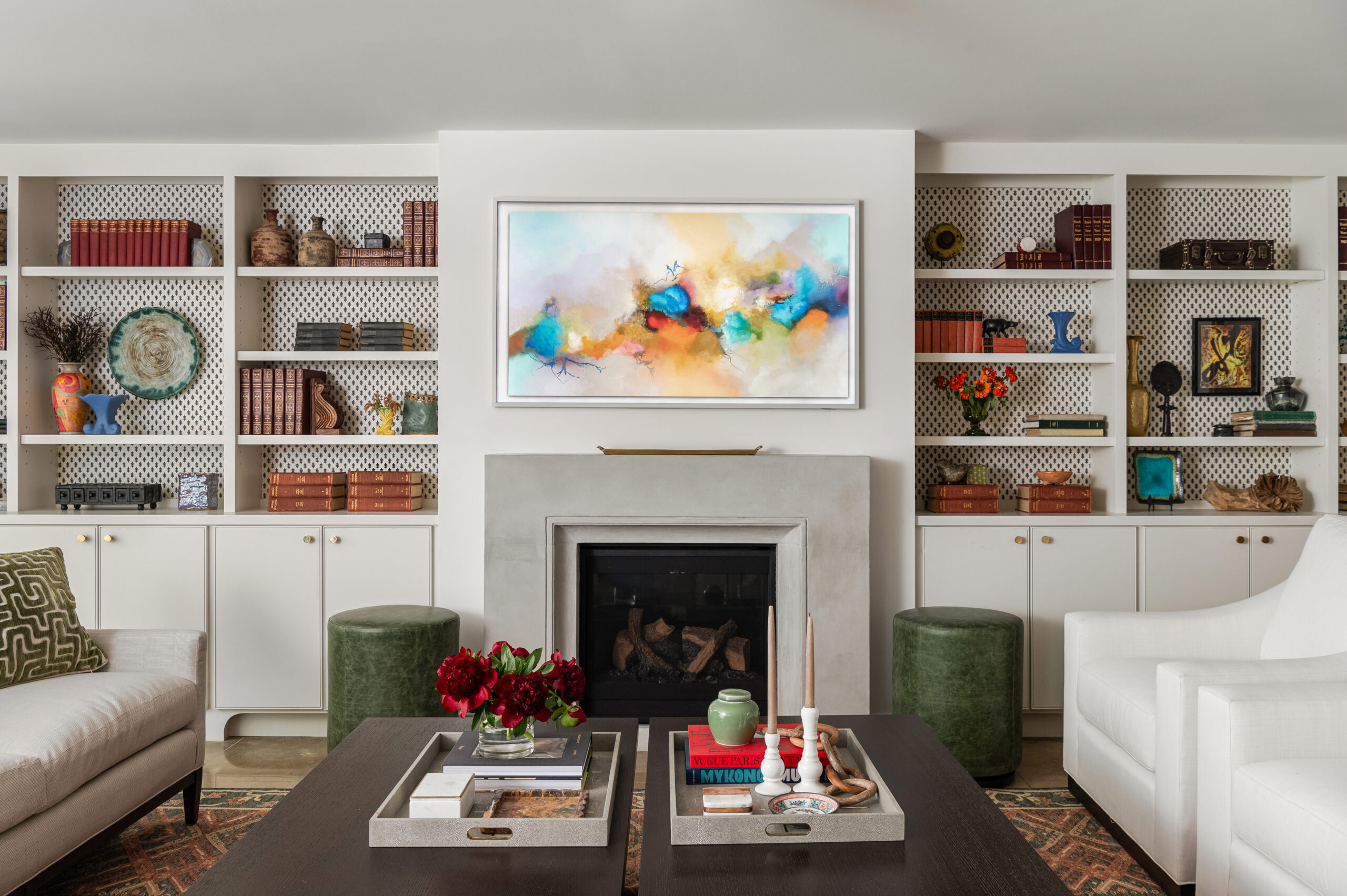 An interior design and photography session showcasing colorful artwork above a fireplace with carefully arranged bookshelves.