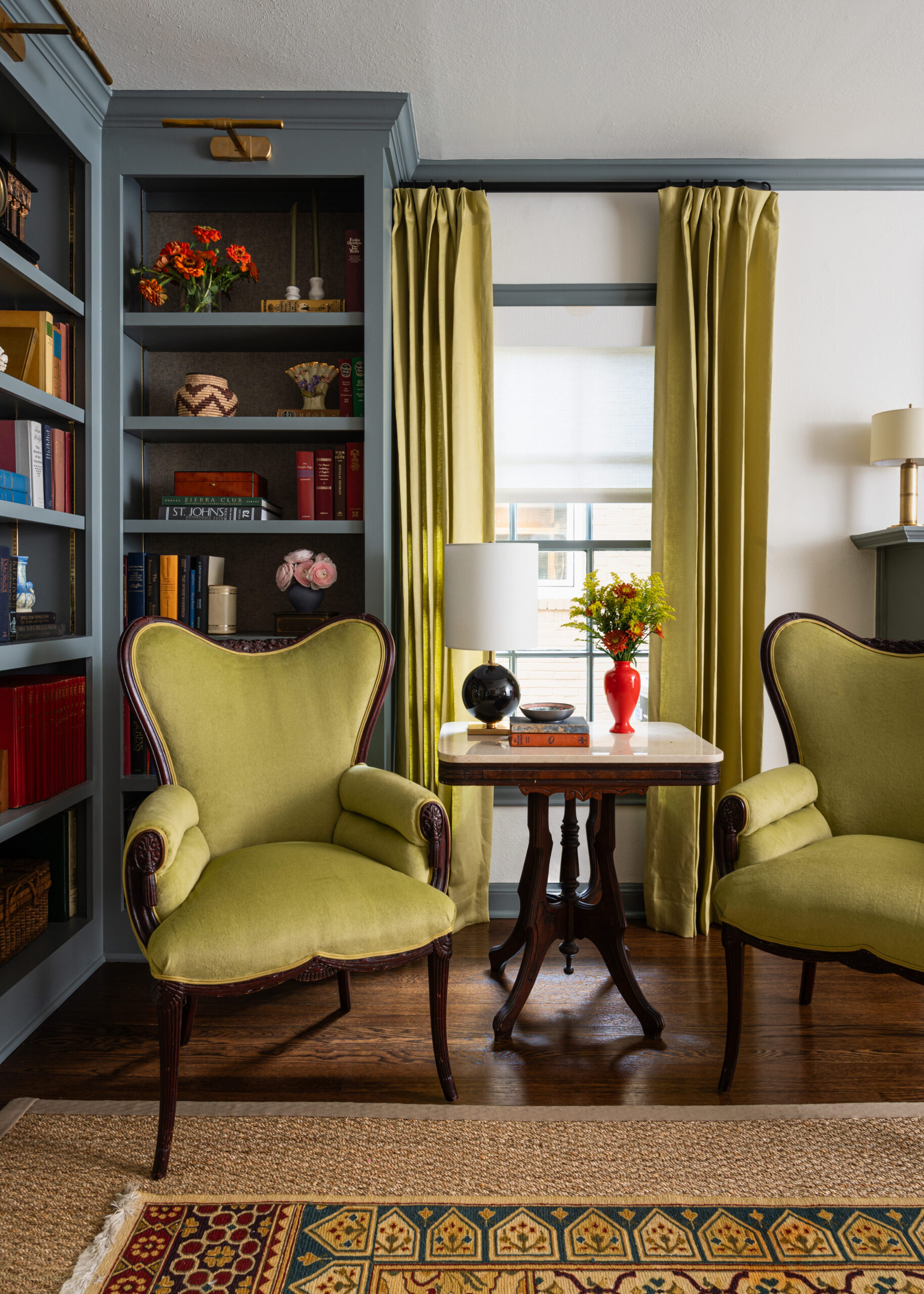 A close-up shot of a vintage green chair with a beautiful, eclectic bookshelf background. The interior design and photography perfectly highlight the color contrast.