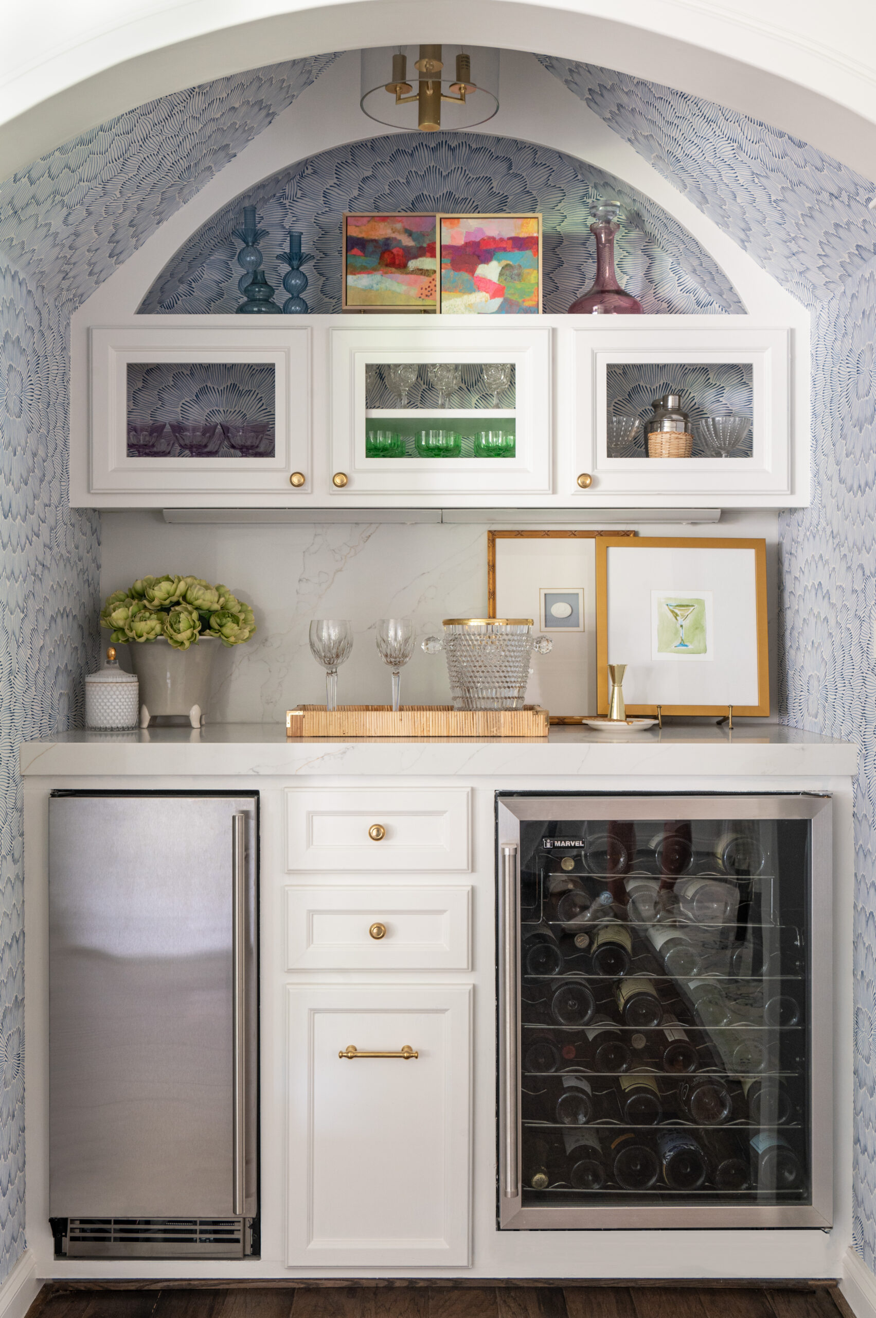 A chic bar nook with a wine fridge, stylish glassware, and vibrant artwork. The use of bold colors and strategic placement of decor mirrors the thoughtfulness of master interior design in creating functional yet visually stunning spaces