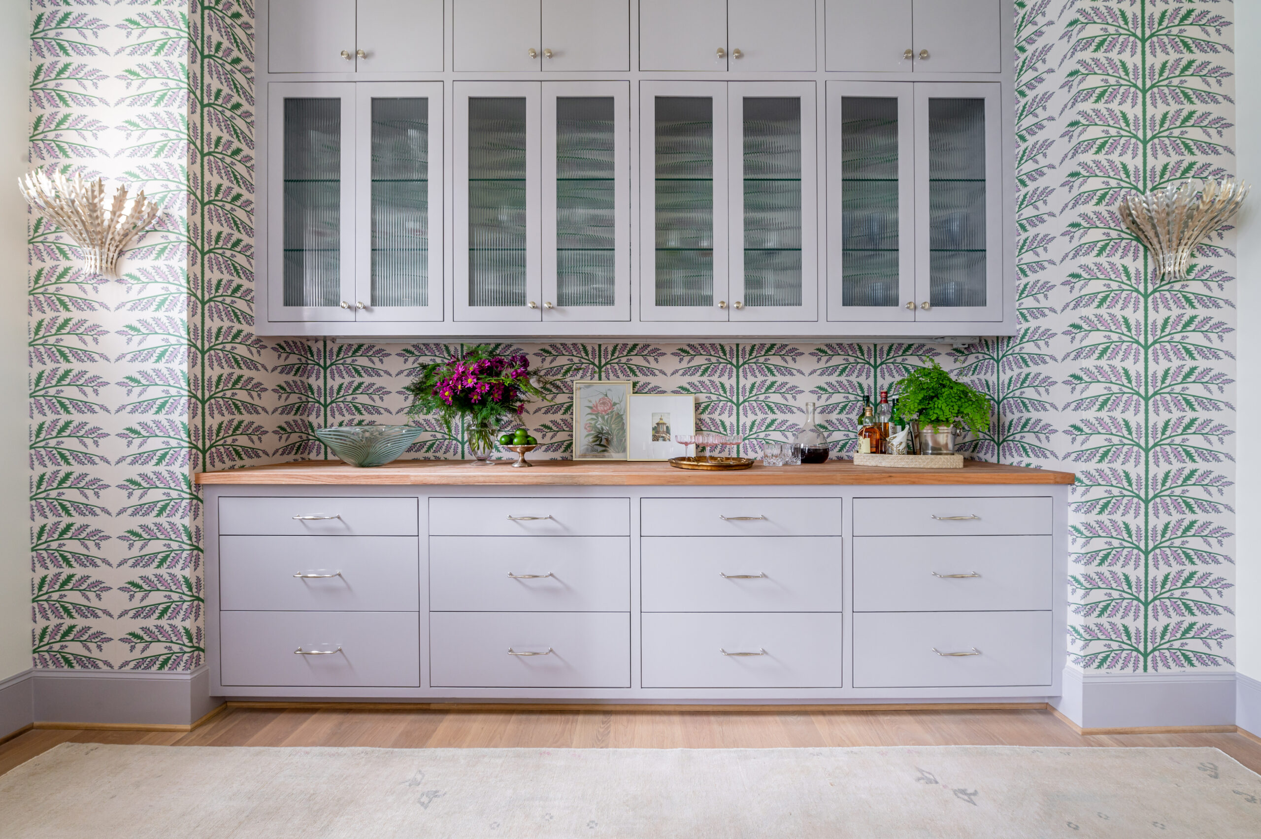 A stylish bar nook with green drinks and stylish glassware displayed on a wooden countertop, perfect for any chic kitchen in interior design publications.