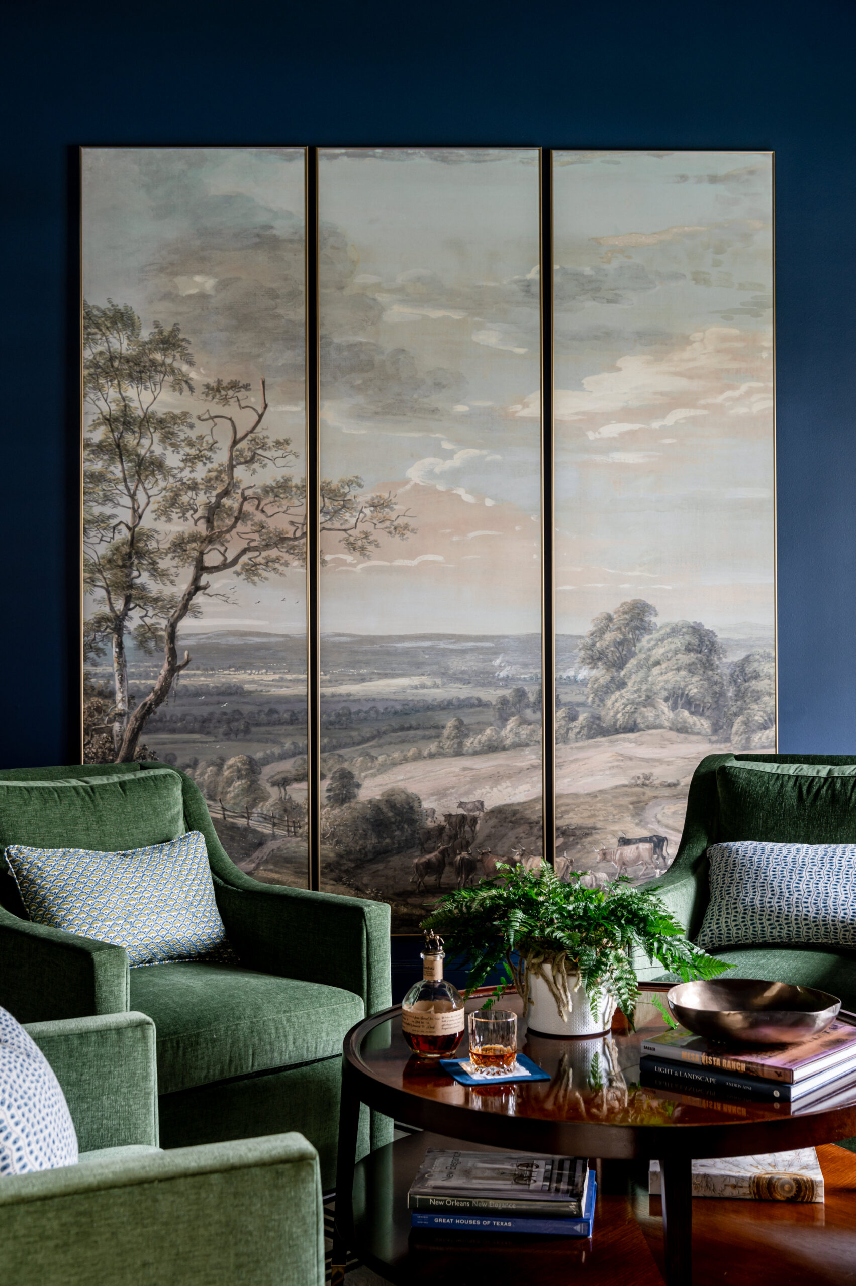 A cozy seating area with green armchairs and a scenic landscape artwork on the wall, perfect for stylish interior design publications.