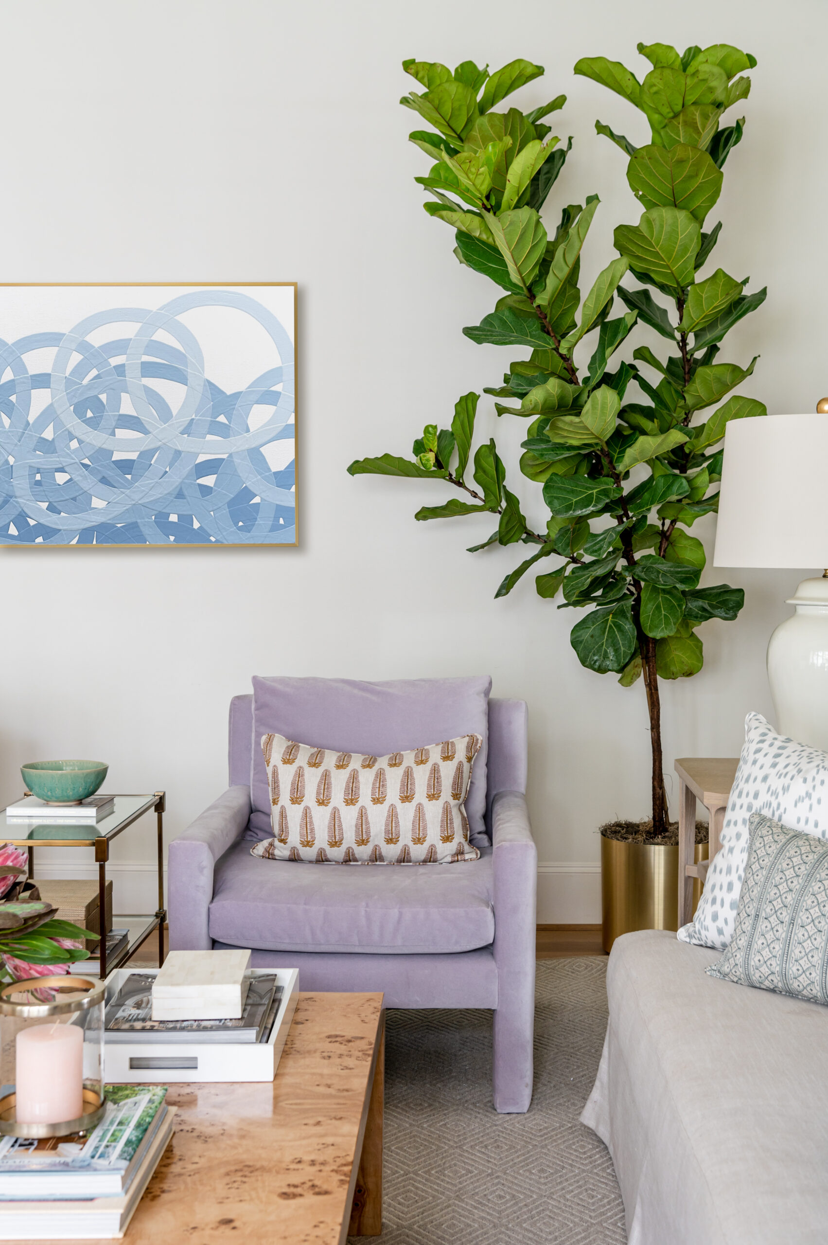 A comfortable reading spot with a large fig tree and decorative art pieces above the seating area, perfect for casual living room designs featured in interior design publications.