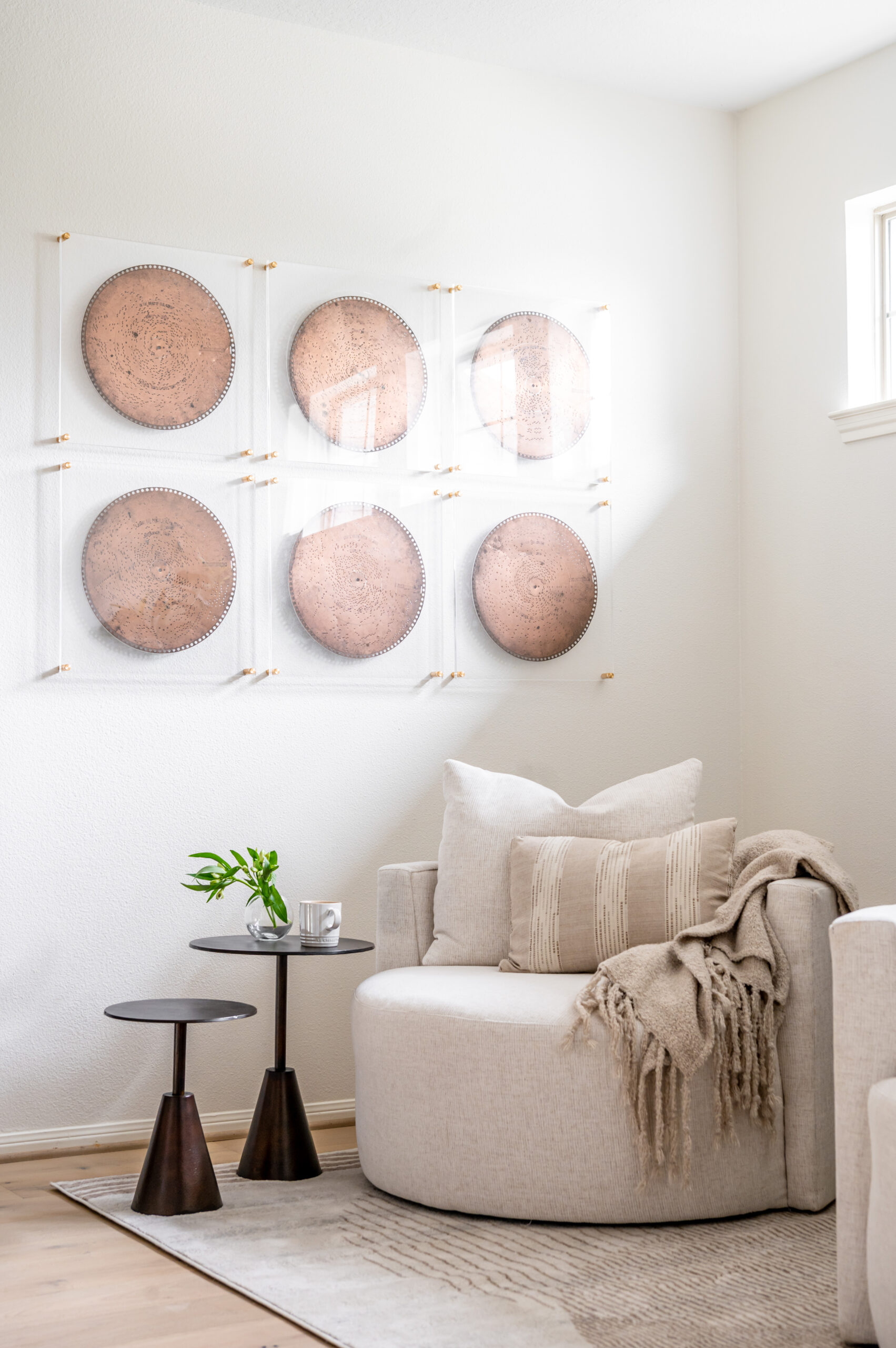 A cozy reading nook featuring a neutral-toned round chair and abstract art on the wall, ideal for an article on minimalist designs in interior design publications.